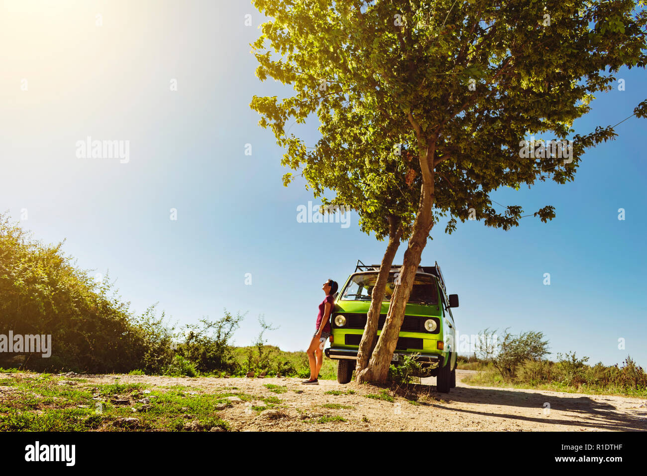 Schöne junge Mädchen in kurzen Hosen stand neben Old Timer classic Wohnmobil unter dem Baum an einem hellen und warmen Sommertag Stockfoto