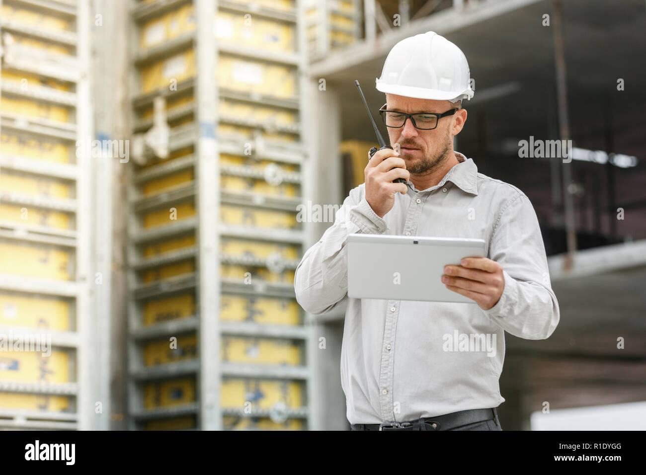 Männliche Leiter Ingenieur tragen weiße Sicherheit hardhat mit Walkie talkie und Tablet Inspektion Baustelle. Technologie, Entwicklung und Bau ich Stockfoto