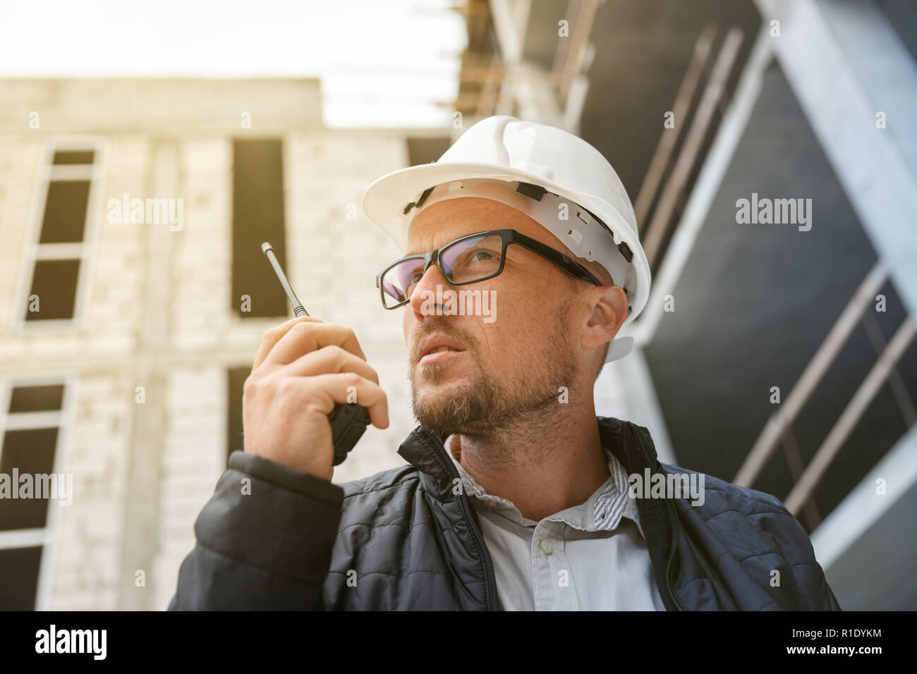 Männliche Leiter Ingenieur tragen weiße Sicherheit hardhat mit Walkie talkie während der Inspektion Baustelle. Entwicklung und Konstruktion Industrie Konzept Stockfoto
