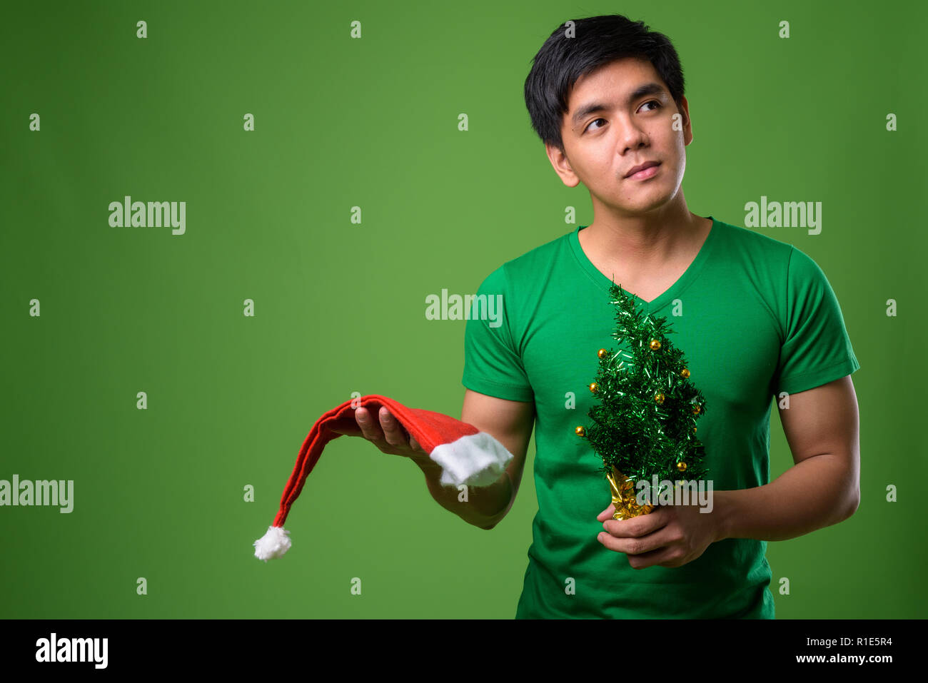 Junge schöne Filipino Mann bereit für Weihnachten gegen grüne Ba Stockfoto