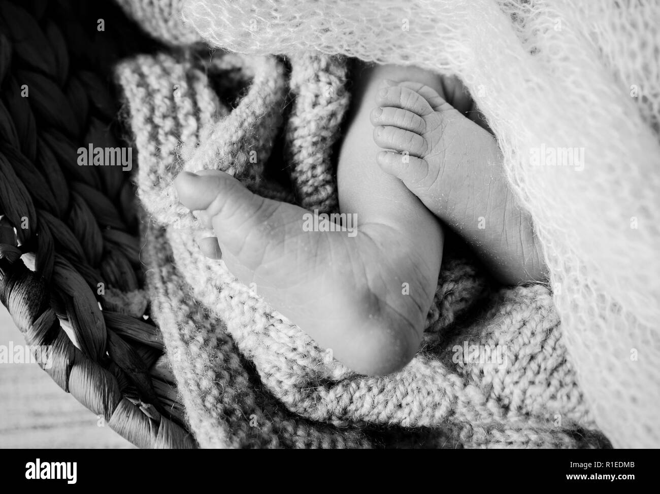 Düstere schwarz-weiß Foto Nahaufnahme eines neugeborenen Babys Füße Zehen unter einem weißen weichen gestrickte Decke, baby Verlust Konzept. Stockfoto