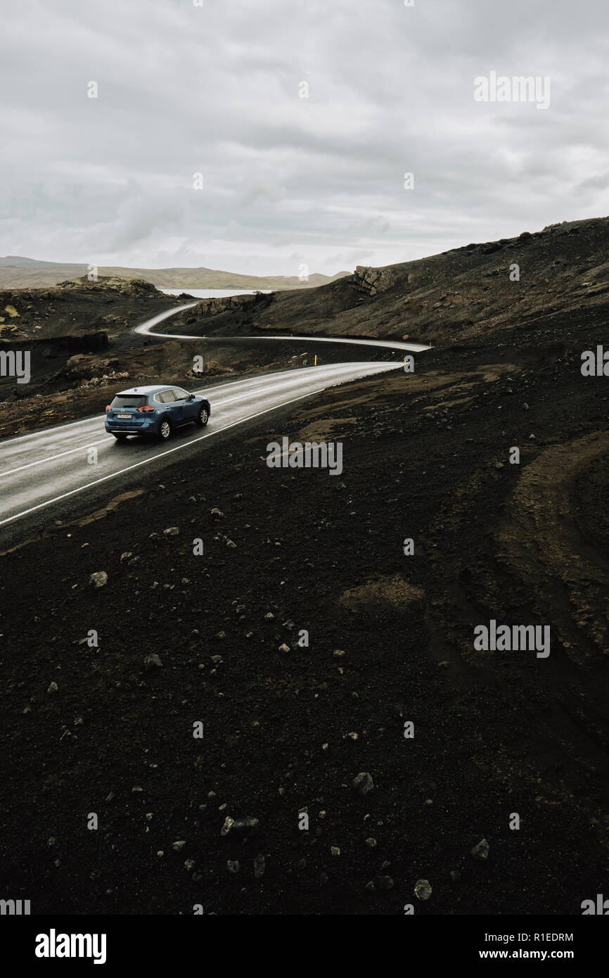 Ein einsames Auto fährt durch den leeren schwarzen vulkanischen Landschaft der Halbinsel Reykjanes im Südwesten Islands Stockfoto