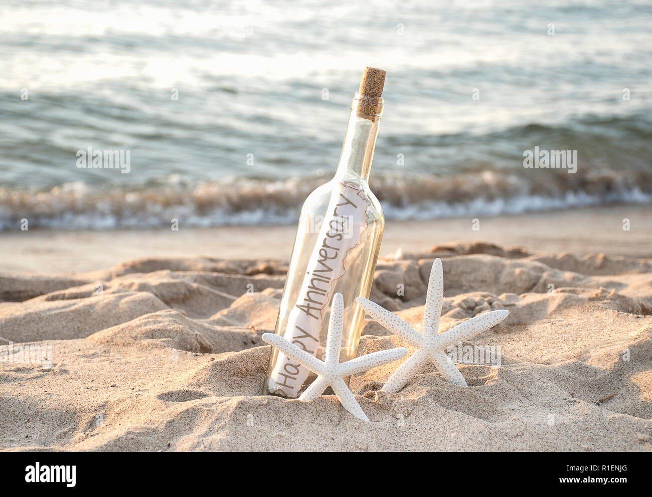 Paar weiße Seesterne in Strand Sand mit herzlichen Glückwunsch Nachricht in einer Flasche, der am Ufer des Meeres Stockfoto