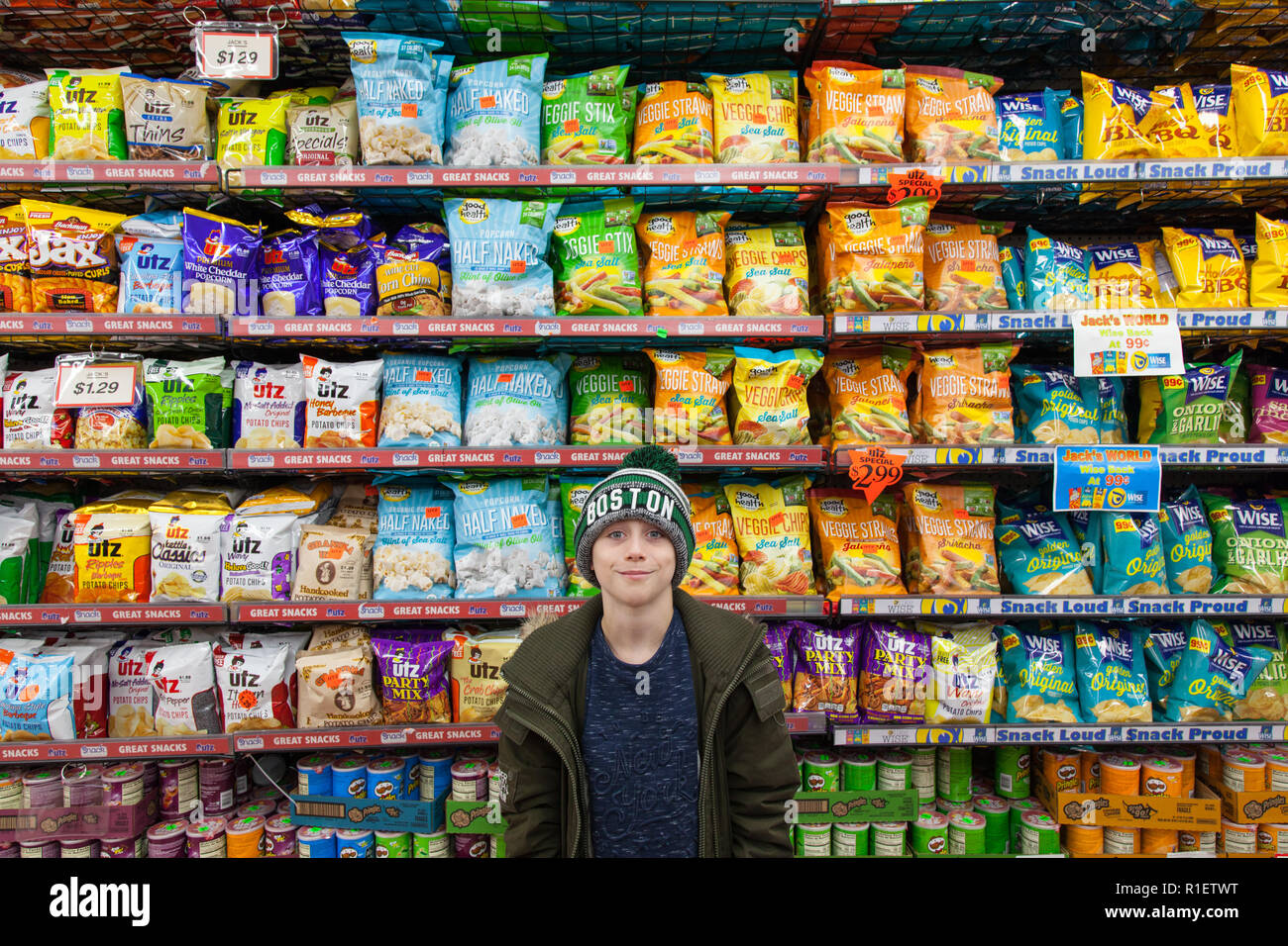 9 Jahre alter Junge vor Regalen der Kartoffelchips, Buchsen store, Midtown, New York City, Vereinigte Staaten von Amerika. Stockfoto