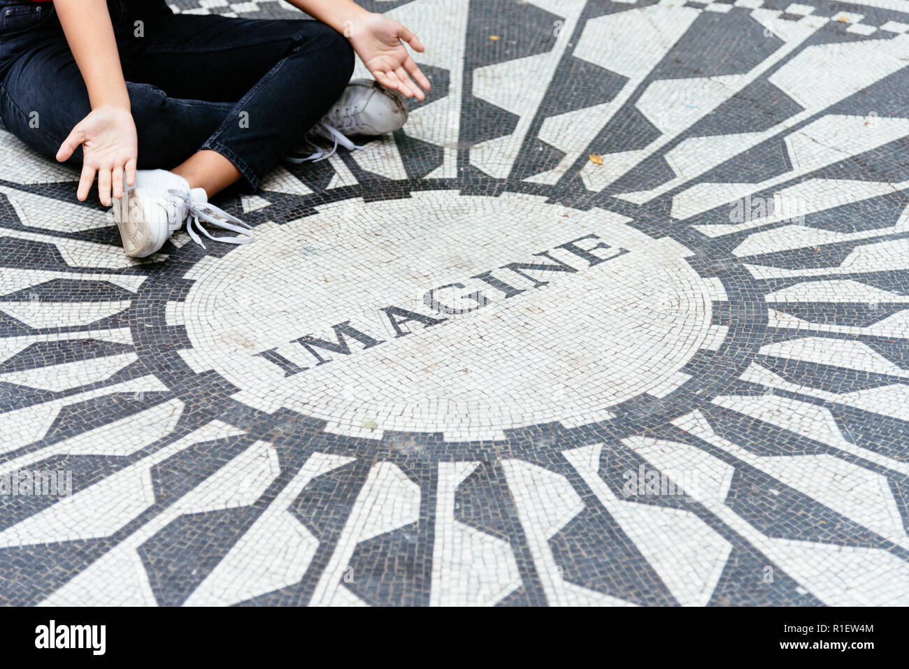 New York City, USA - 23. Juni 2018: junge Frau sitzt auf dem Vorstellen, Mosaik in den Strawberry Fields in Central Park. Stockfoto