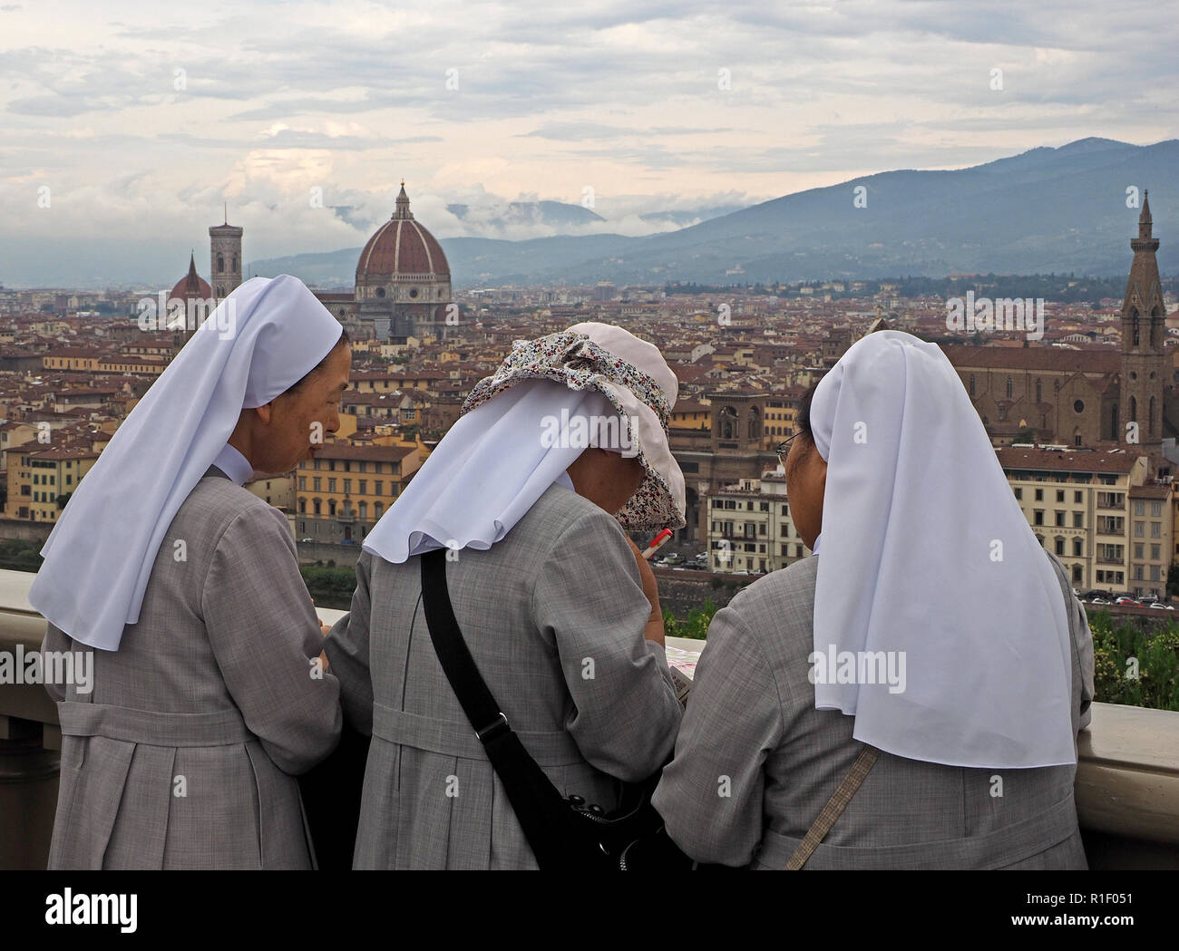 3 Nonnen genießt die Aussicht über Florenz in Richtung Dom und die fernen Hügel von San Miniato Hügel über das Tor von San Niccolò Florenz, Italien Stockfoto