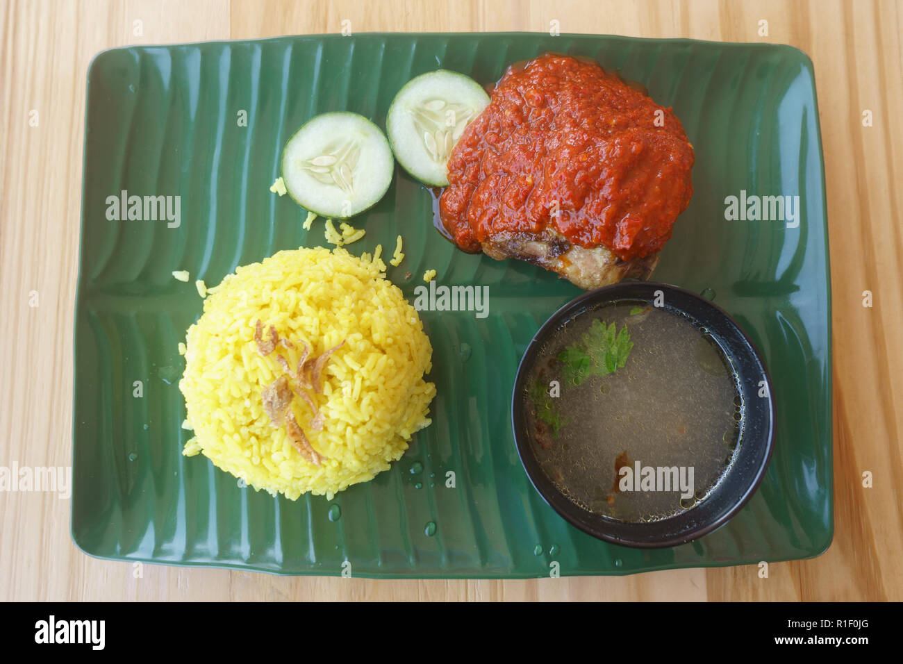 Örtliche Spezialität, Nasi Kuning. Gelber Reis mit Huhn und Chili Quelle. Stockfoto