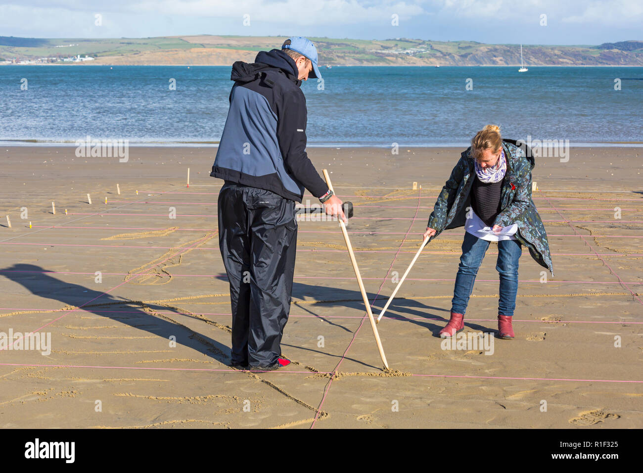 Arbeit erhält unterwegs bei Weymouth Beach auf Danny Boyle's Seiten, wo ein Porträt eines Einzelnen von WW1 aus dem Sand entsteht, Dorset UK Stockfoto