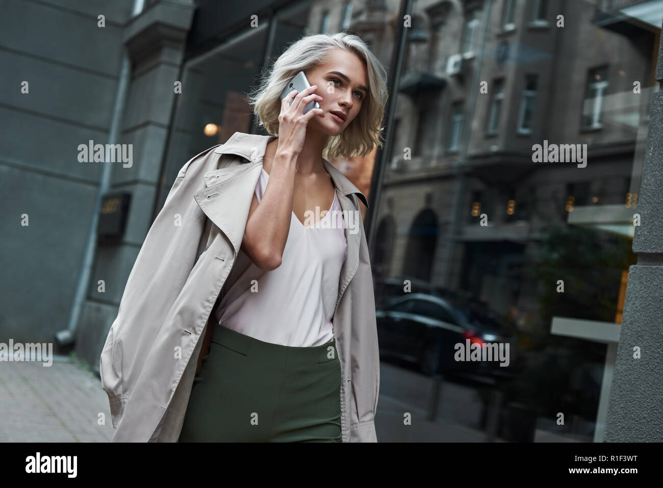 Mode. Junge stilvolle Frau, die zu Fuß auf der Straße reden auf dem Smartphone mit Freund beiseite schaut nachdenklich Stockfoto