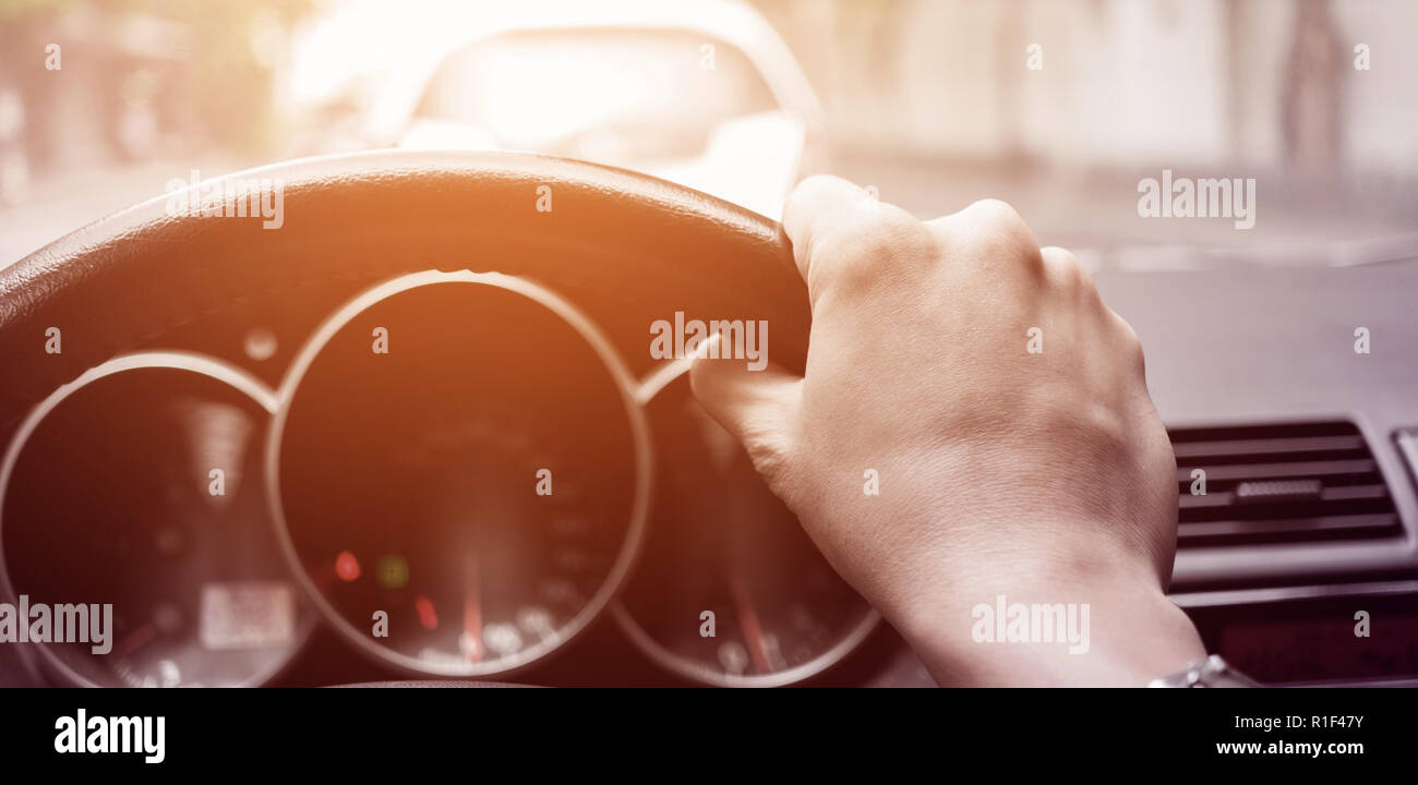 Mit der rechten Hand das Lenkrad beim Fahren Auto. Stau und Sonnenlicht durch das Glas scheinen Stockfoto