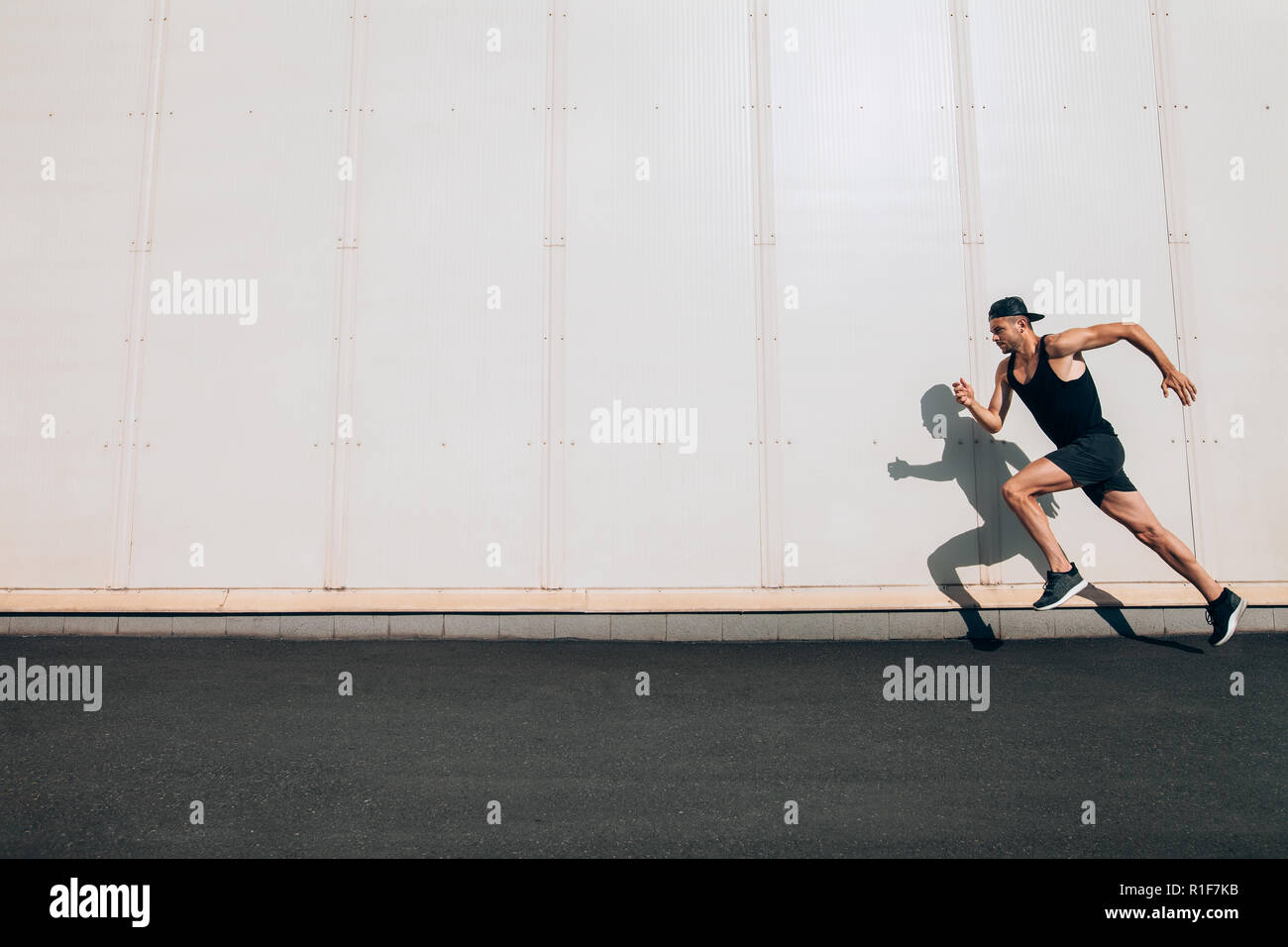 Junger Mann Läufer entlang der Wand mit Kopie Raum läuft. Sport, Fitness, Joggen Stockfoto