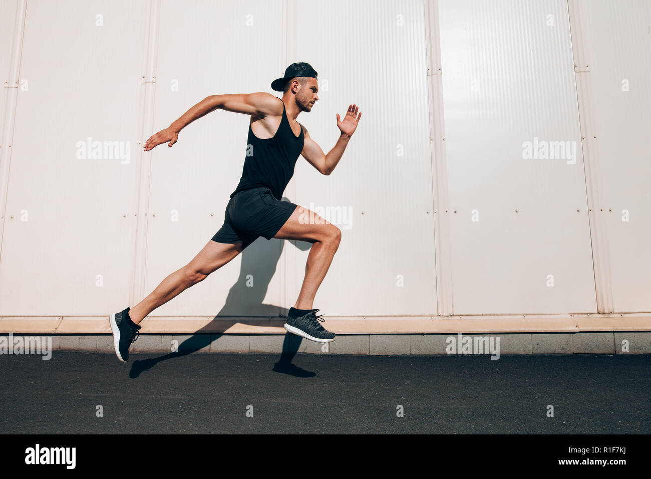 Junger Mann Läufer entlang der Wand mit Kopie Raum läuft. Sport, Fitness, Joggen Stockfoto