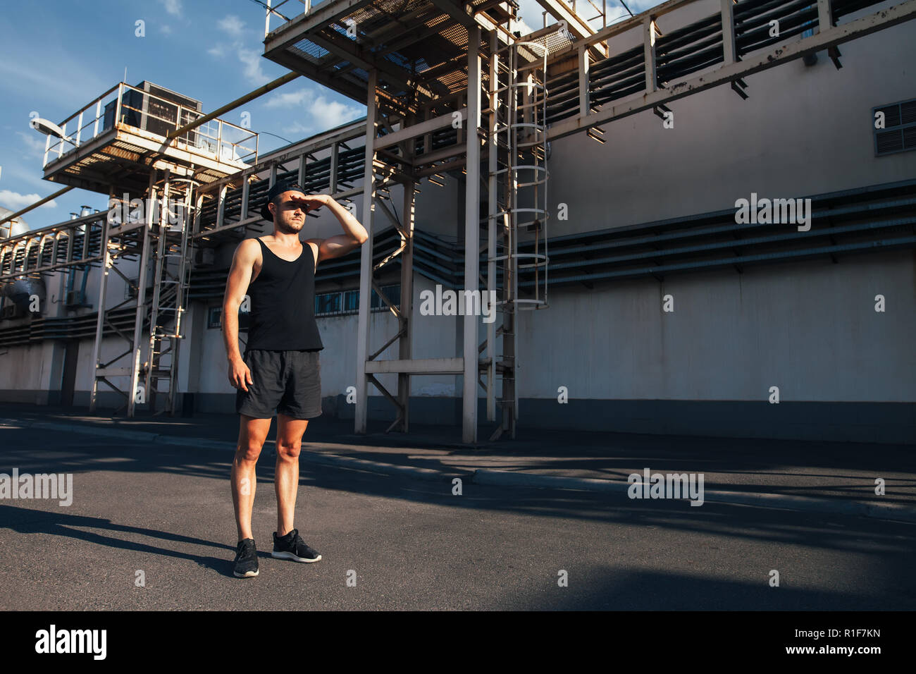 Junge Athlet Mann für Betrieb und weg schauen auf industrielle Gebäude Hintergrund vorbereiten Stockfoto
