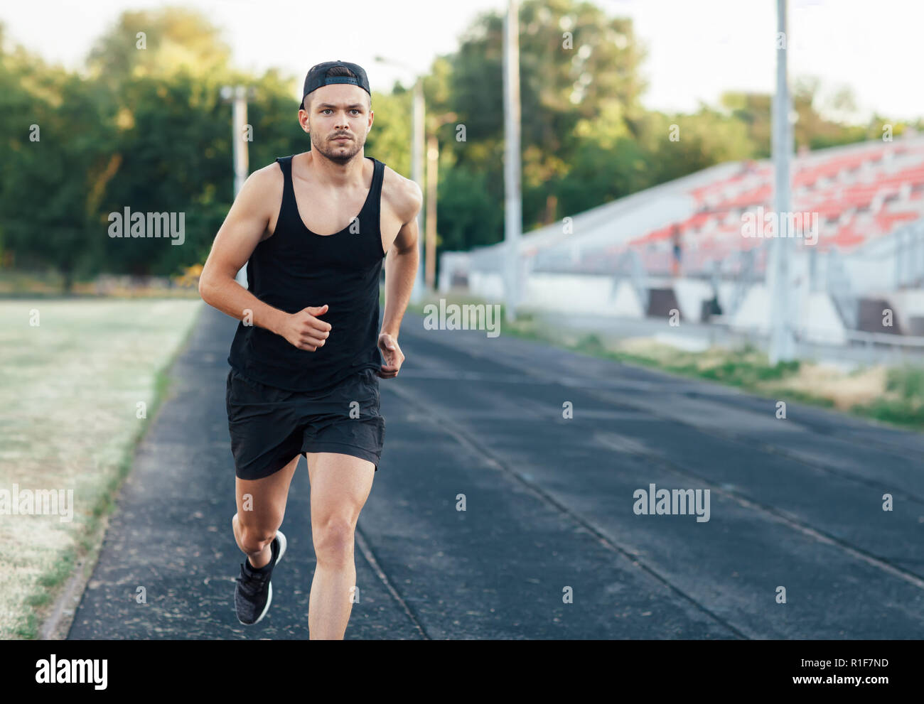 Jungen gutaussehenden Mann laufen auf eine Laufbahn in einem Stadion. Sport, Leichtathletik, Joggen Stockfoto