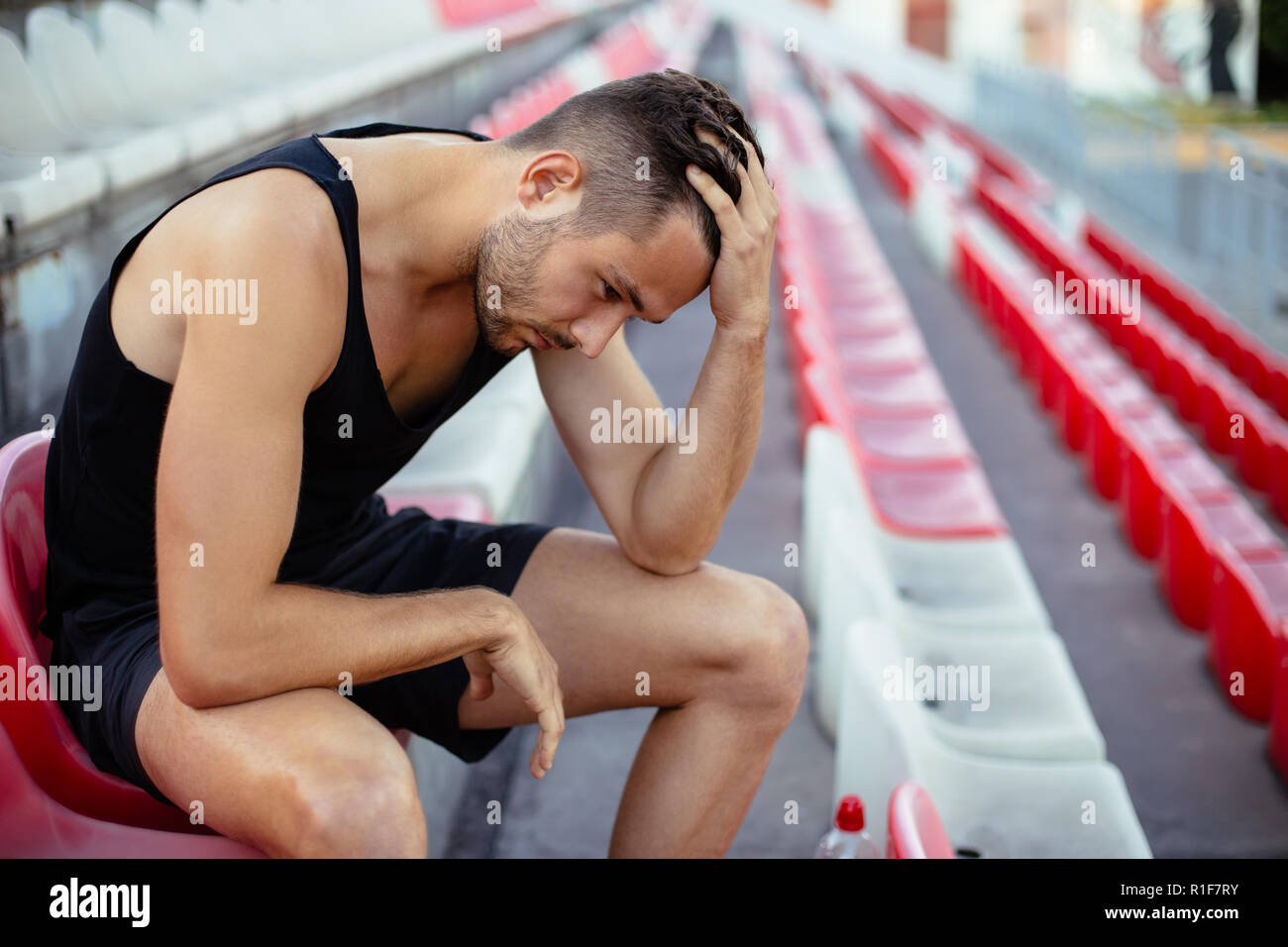 Deprimiert Athlet mann Kopf in den Händen im Stadion sitzen, Stress und traurig Konzept Stockfoto