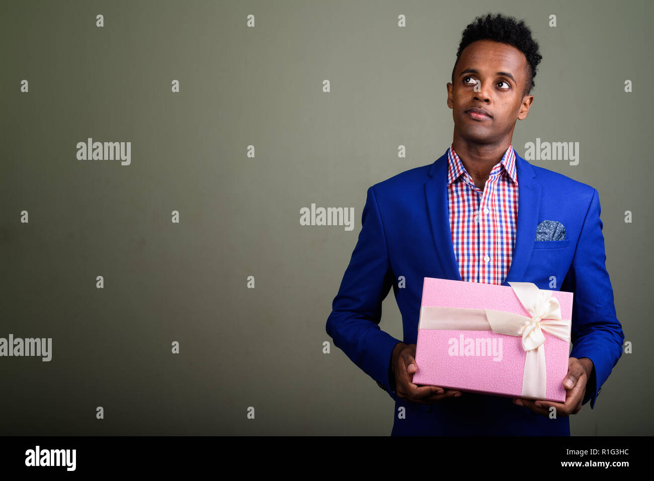 Jungen schönen afrikanischen Geschäftsmann holding Geschenkbox gegen colo Stockfoto