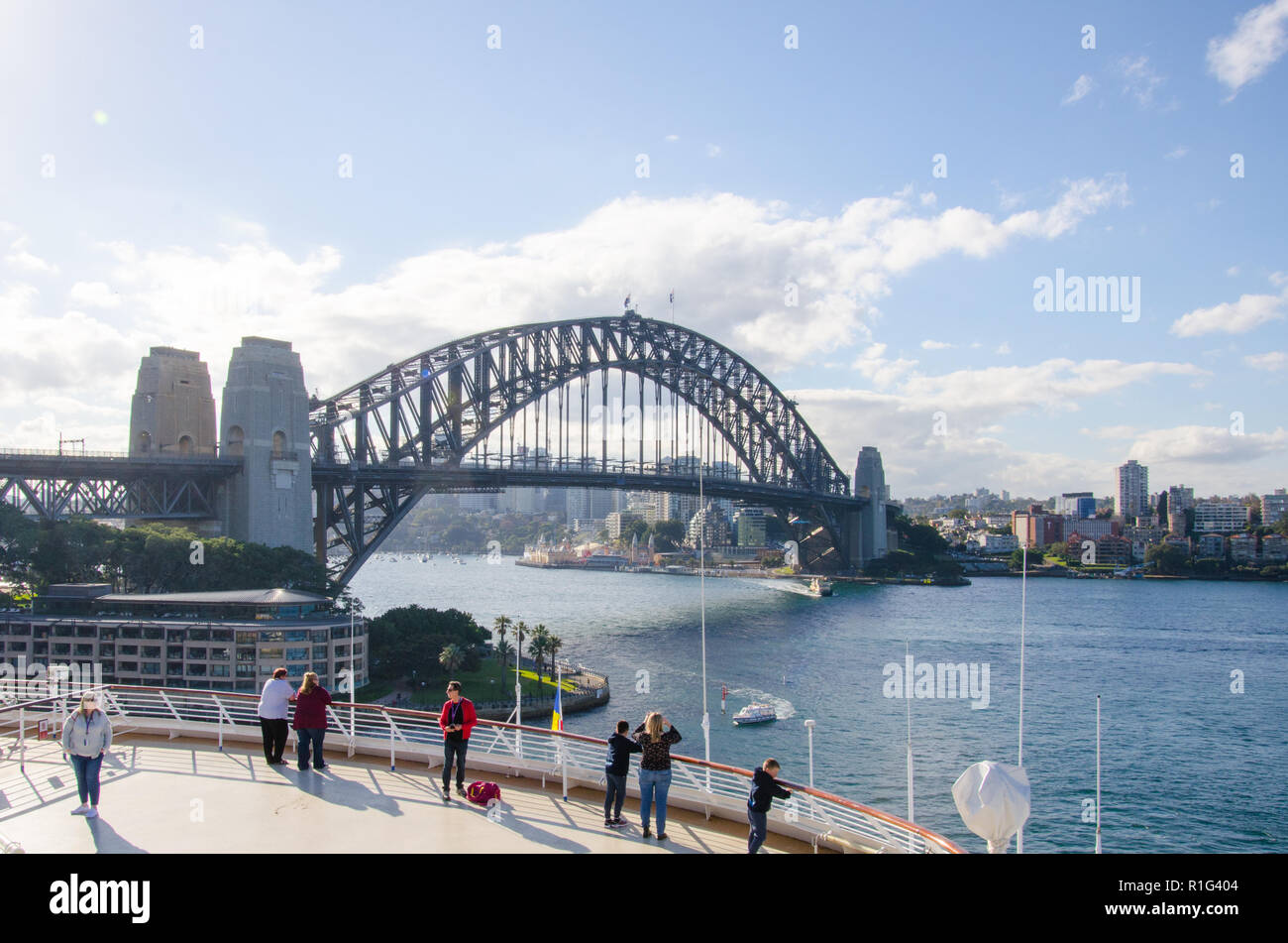 Die Passagiere genießen Sie den schönen Blick auf die Wahrzeichen von Sydney Harbour Bridge vom Deck eines Kreuzfahrtschiffes an der Sydney Cove Passenger Terminal angedockt. Stockfoto