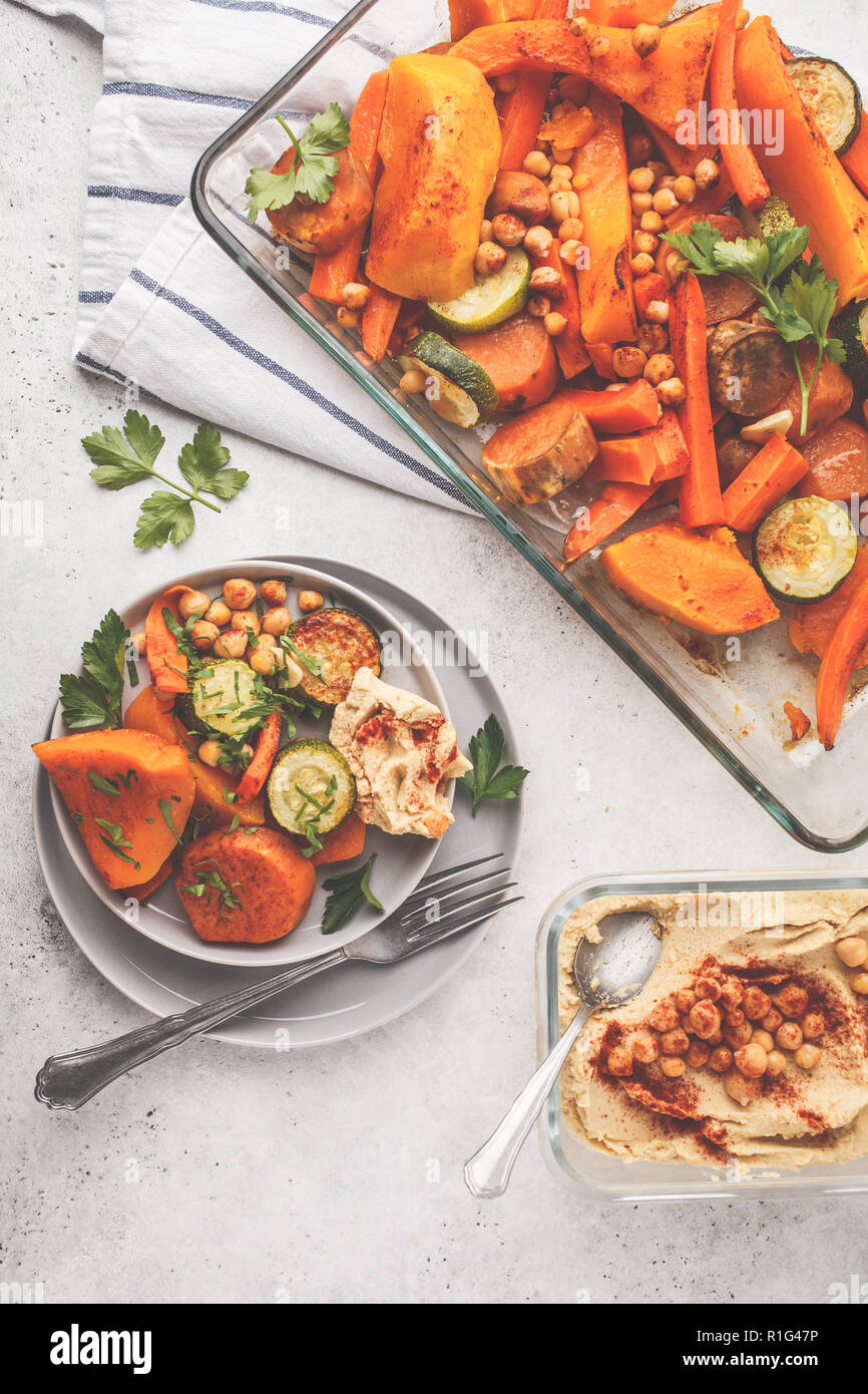 Gebackene Gemüse (Karotten, Zucchini, Kartoffel, Kürbis) mit Kichererbsen und Hummus, Ansicht von oben. Auf Basis pflanzlicher Ernährung Konzept. Stockfoto