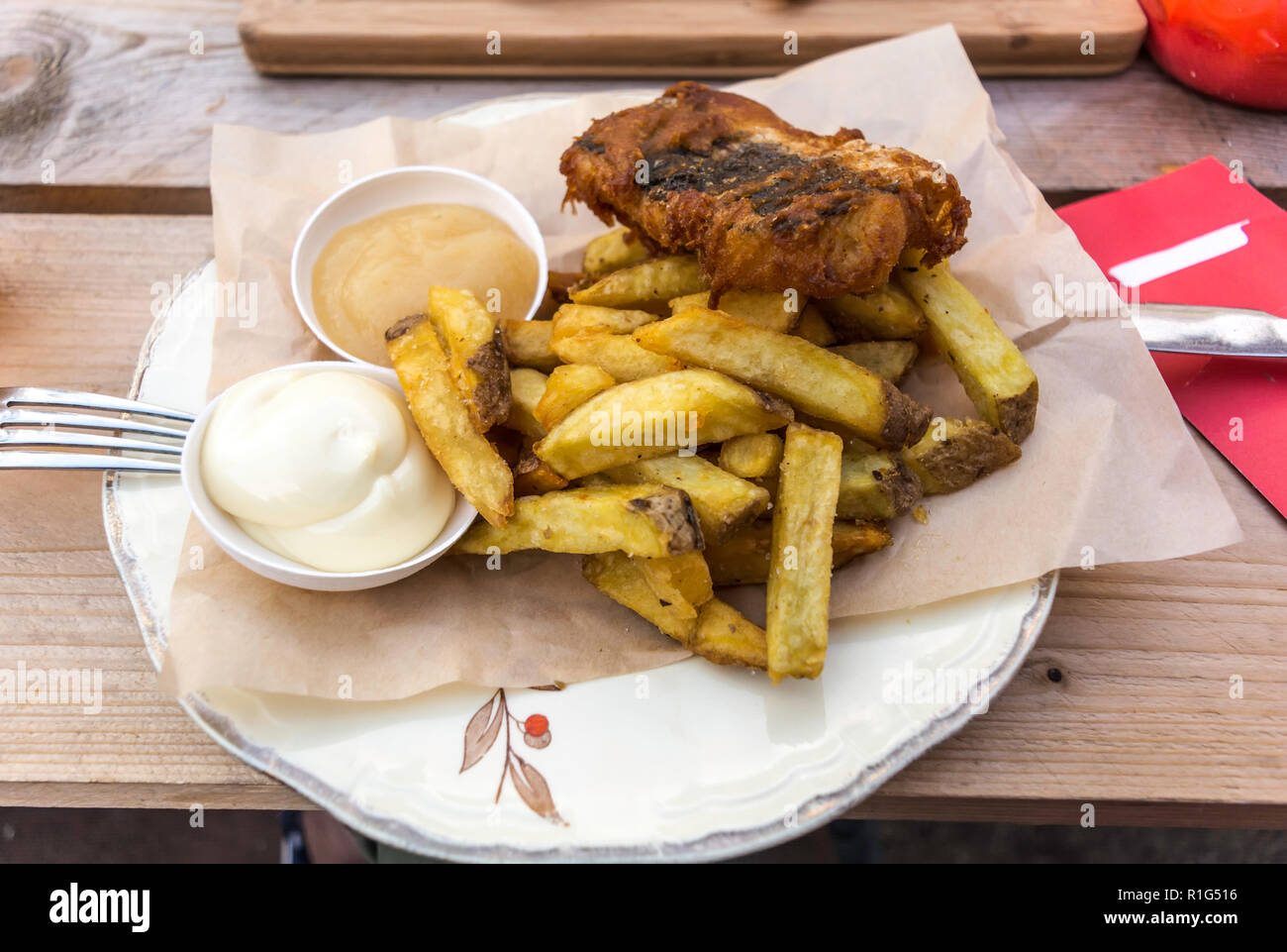 Fisch und Pommes mit Curry und Sauce auf einer Platte mit einem Papier Tatar serviert. Es ist ein warmes Gericht englischer Herkunft, bestehend aus gebratenen zerschlagene Fisch und Ho Stockfoto