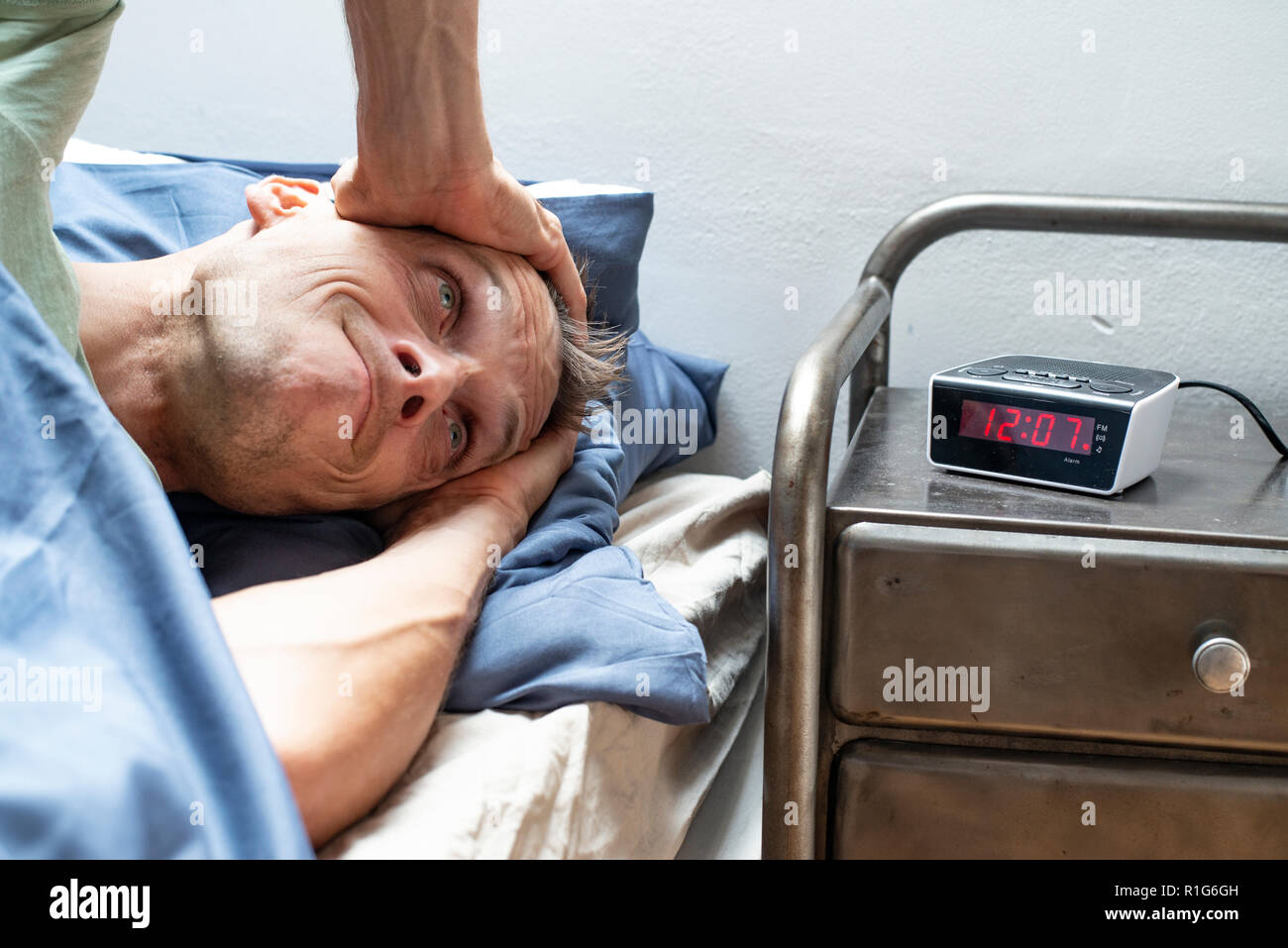 Man verschlafen, zu spät zur Arbeit. In seinem Bett an der Wecker suchen Stockfoto