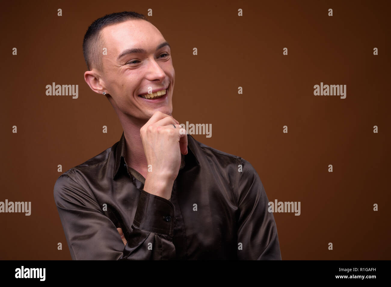Junge schöne androgyne Geschäftsmann gegen braunen Hintergrund Stockfoto