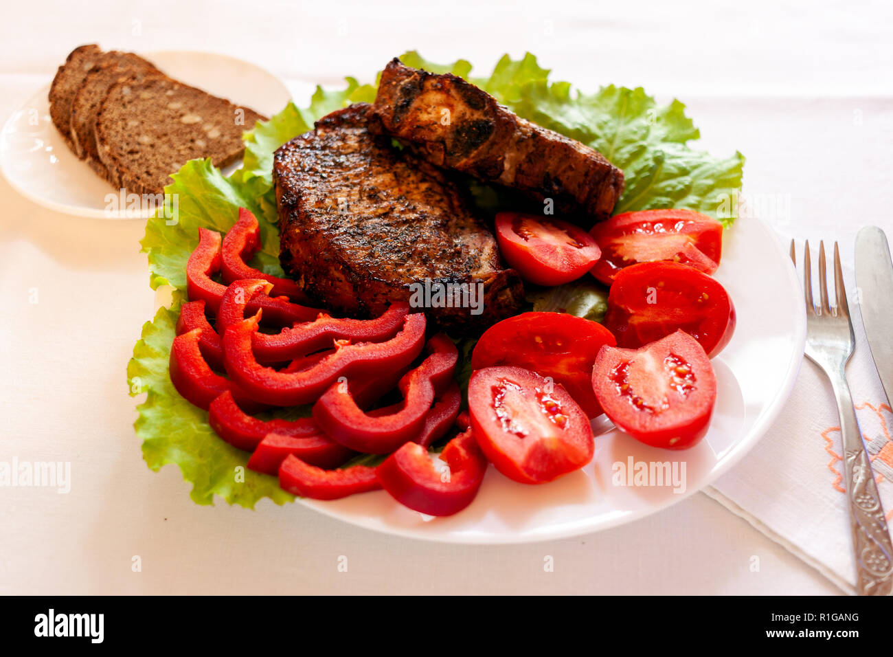 Schweinefleisch vom Grill das Fleisch auf einen Teller mit frischem Gemüse Stockfoto