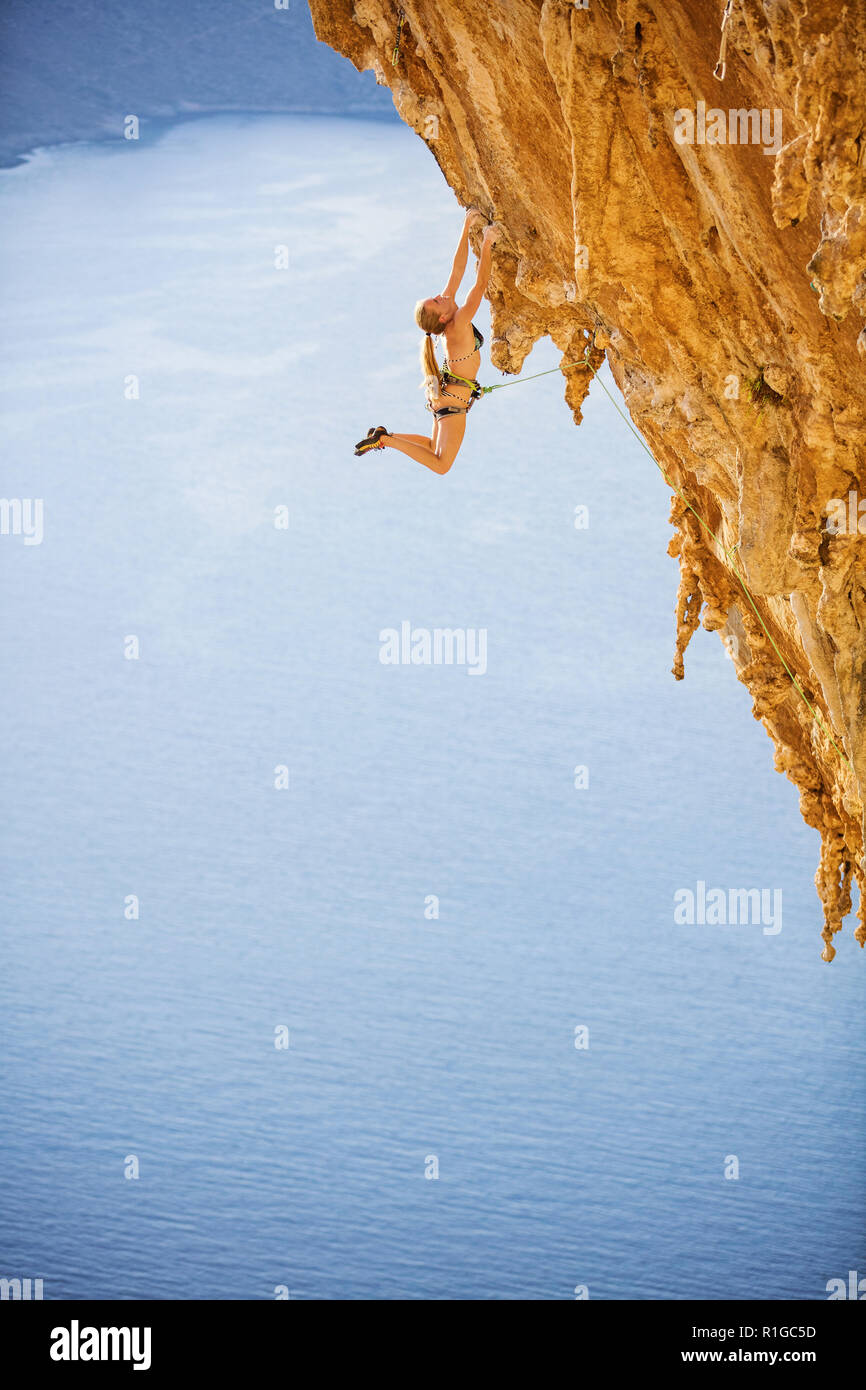 Female Rock climber Springen auf haltegriffe auf anspruchsvolle Strecke auf einer Klippe, Insel Kalymnos, Griechenland Stockfoto