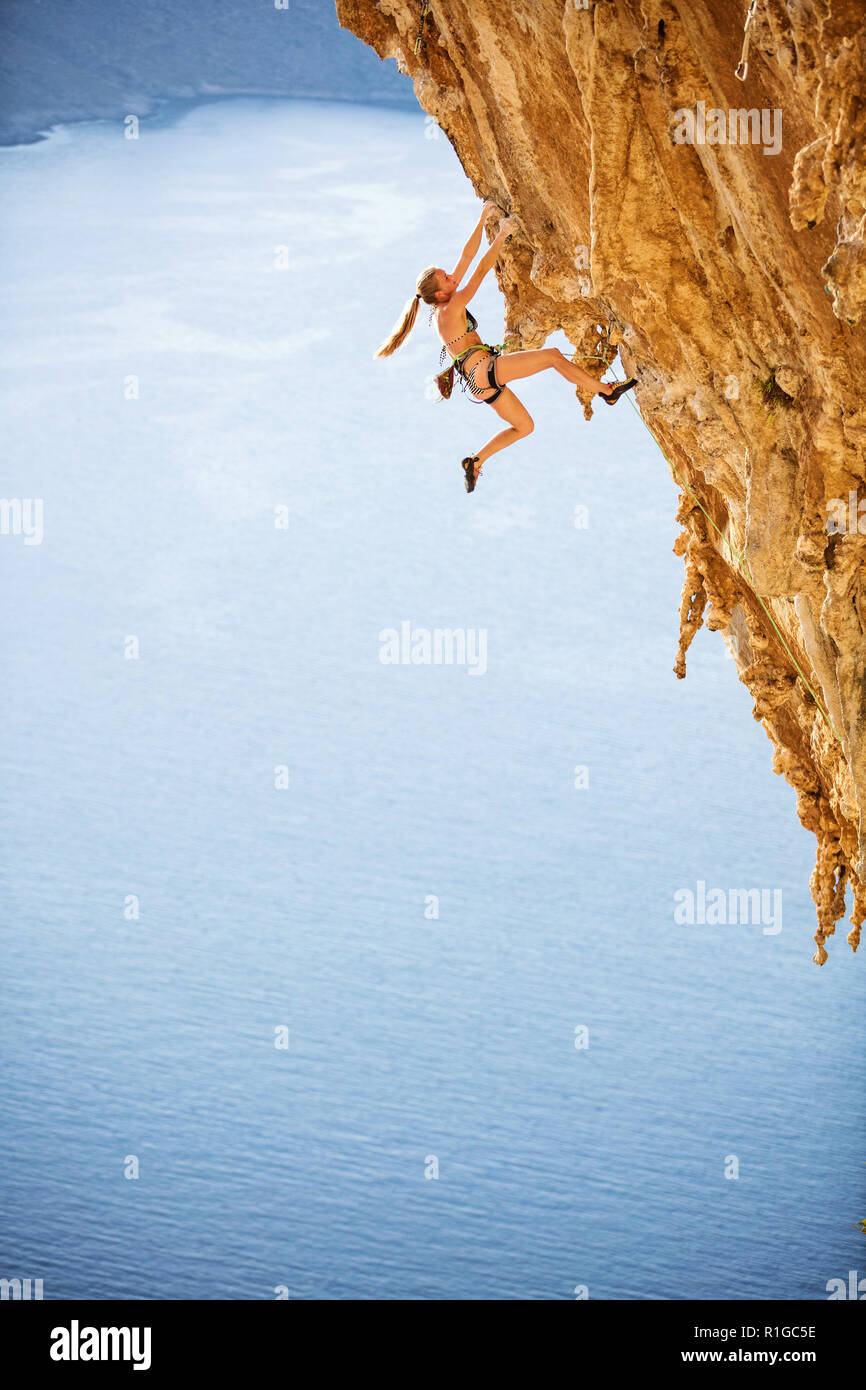Junge weibliche Kletterer tragen Bikini auf anspruchsvolle Strecke auf einer Klippe Stockfoto