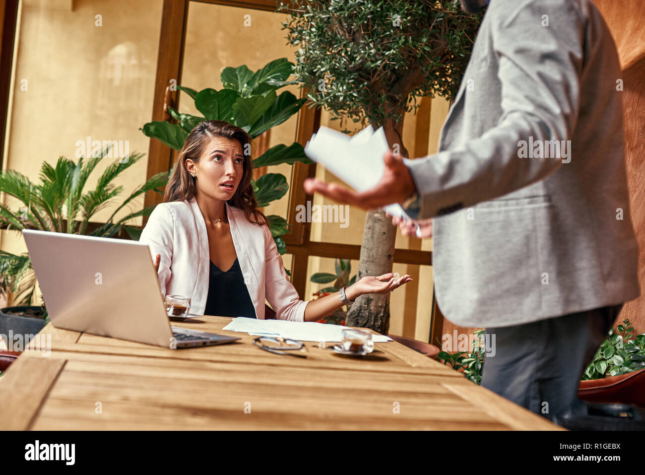 Business Lunch. Frau sitzt am Tisch, während man standing Hände beiseite argumentieren irritiert close-up Stockfoto