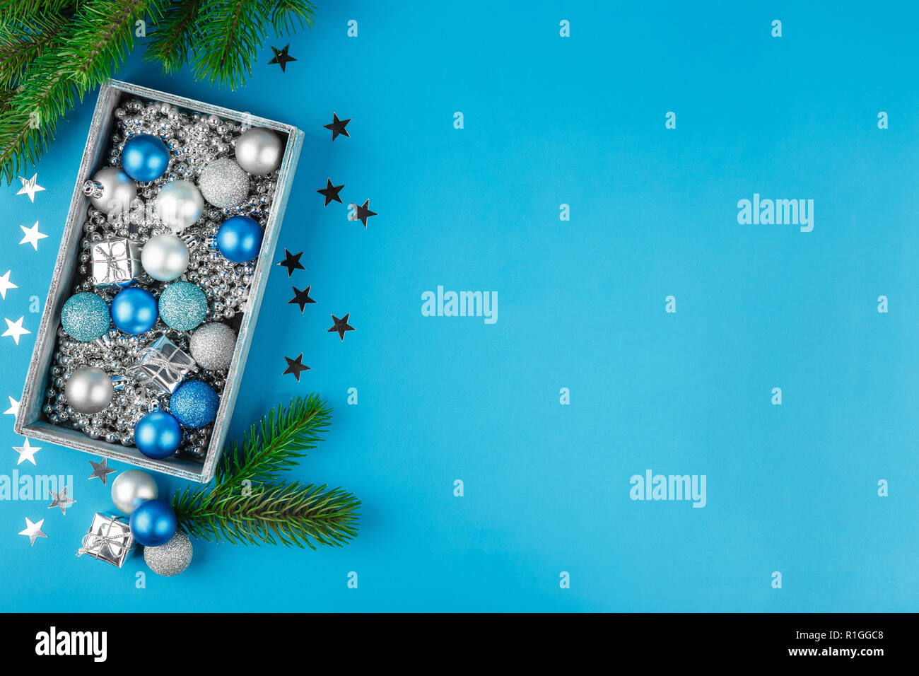 Weihnachten blau und silber Kugeln silber Weihnachten Perlen in einer Holzkiste auf blauem Hintergrund. Flach. Festlicher Rahmen für Grußkarte Stockfoto