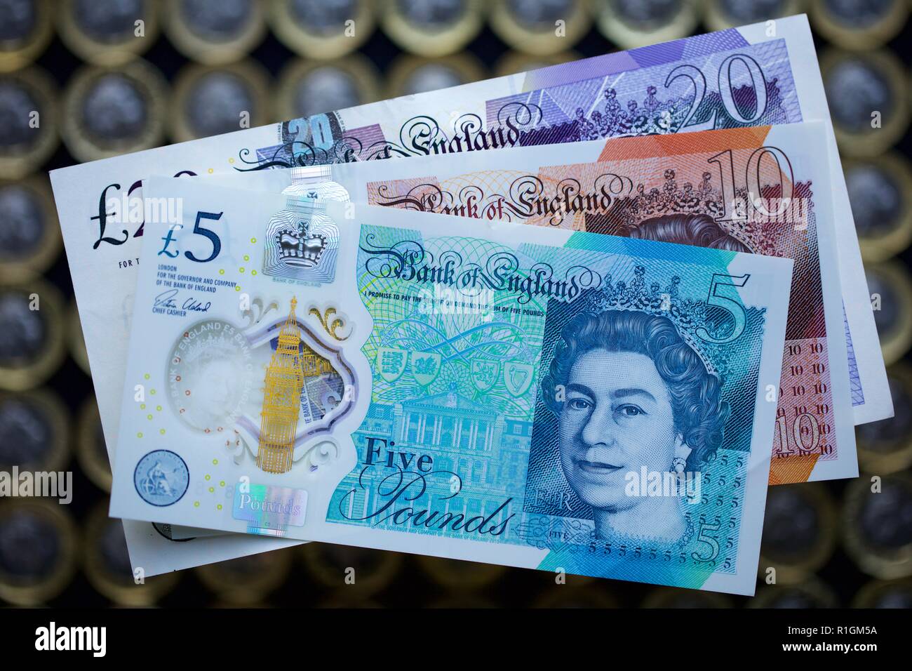 Britische Banknoten mit dem neuen 12-seitigen Pfund Münzen im Hintergrund Stockfoto