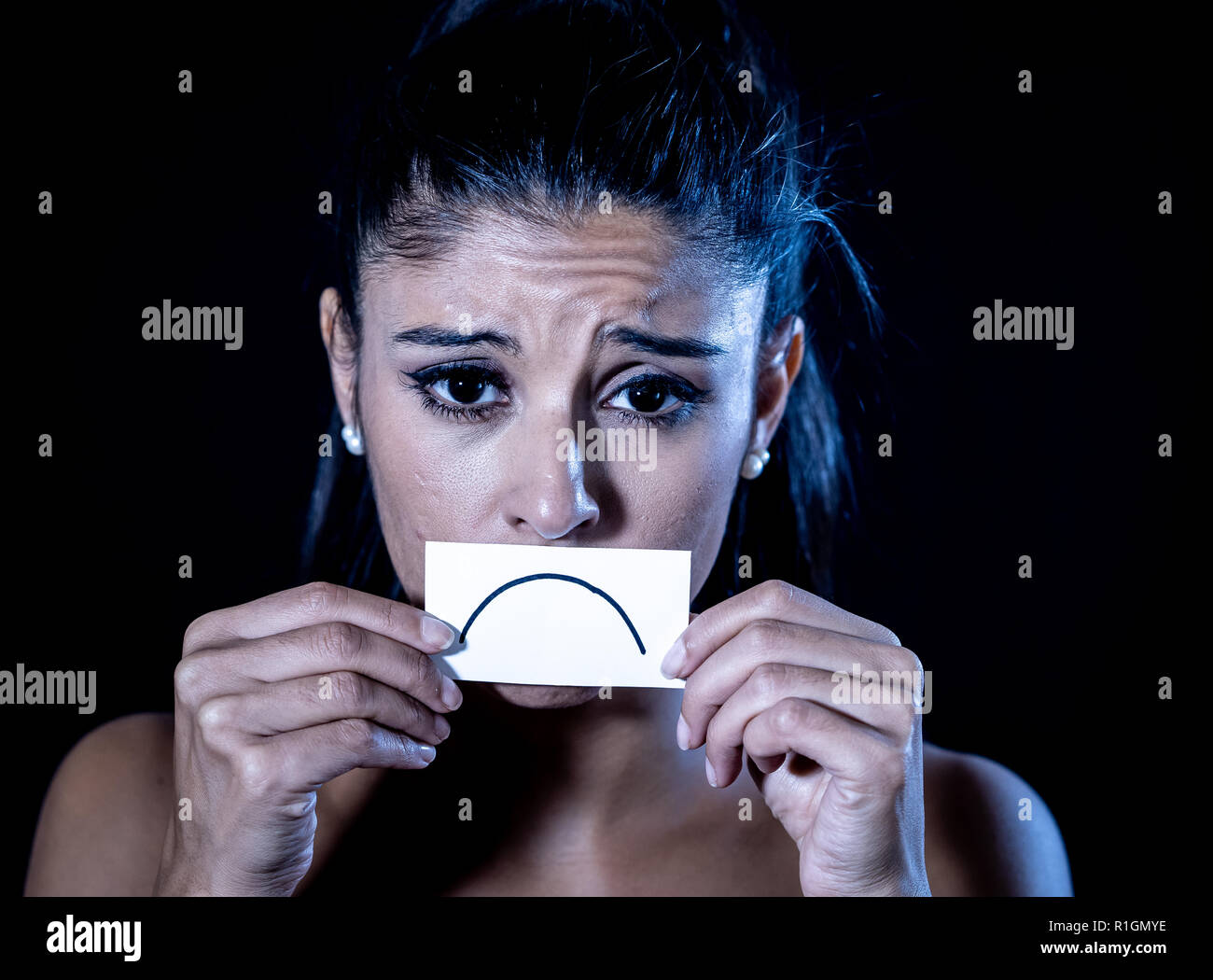 Close up Portrait von traurigen attraktive junge Latin Frau unter Depressionen leiden in dramatische Beleuchtung auf schwarzem Hintergrund isoliert. Stockfoto