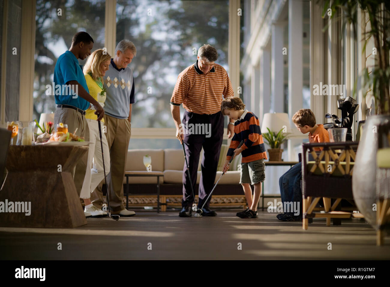 Jungen erhalten, Golf Tipps aus seiner Mitte nach Vater, wie seine Mutter und zwei Männer beobachten. Stockfoto