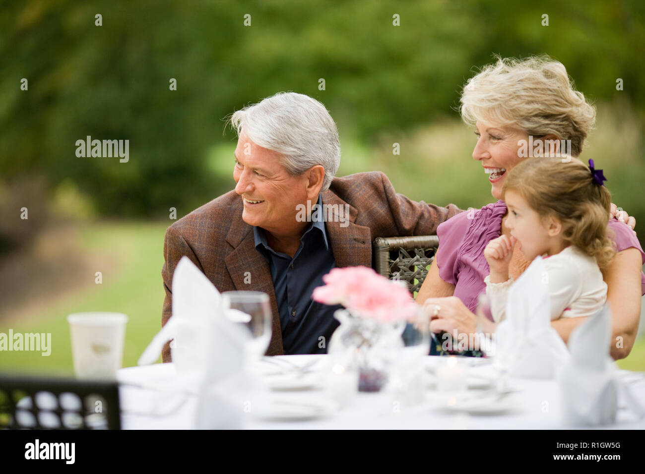 Reifen erwachsenen Paar mit ihren jungen Enkelin bei der äußeren Tabelle der ein Restaurant. Stockfoto