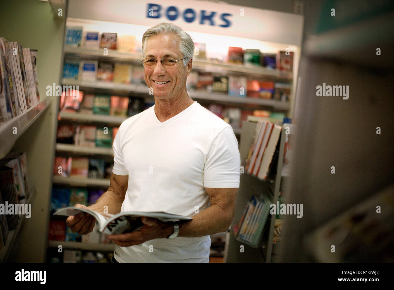 Porträt eines lächelnden reifer Mann eine Zeitschrift in einem Buchladen. Stockfoto