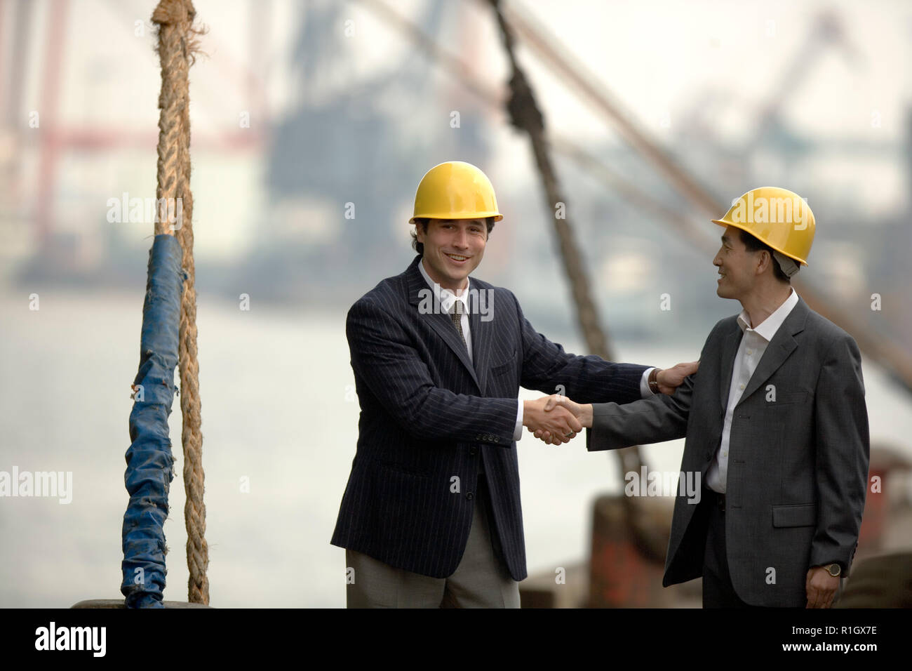 Porträt eines jungen Erwachsenen Geschäftsmann Händeschütteln mit einem mittlerem - Erwachsene Geschäftsmann auf einem Wharf. Stockfoto