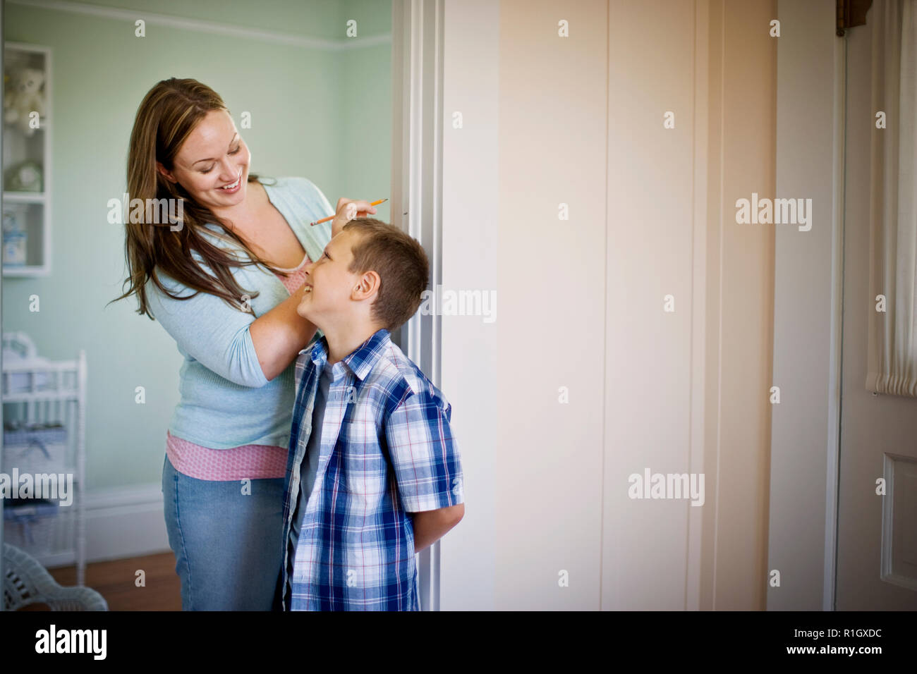 Mitte der erwachsenen Frau ihren Sohn Messen gegen eine Wand. Stockfoto
