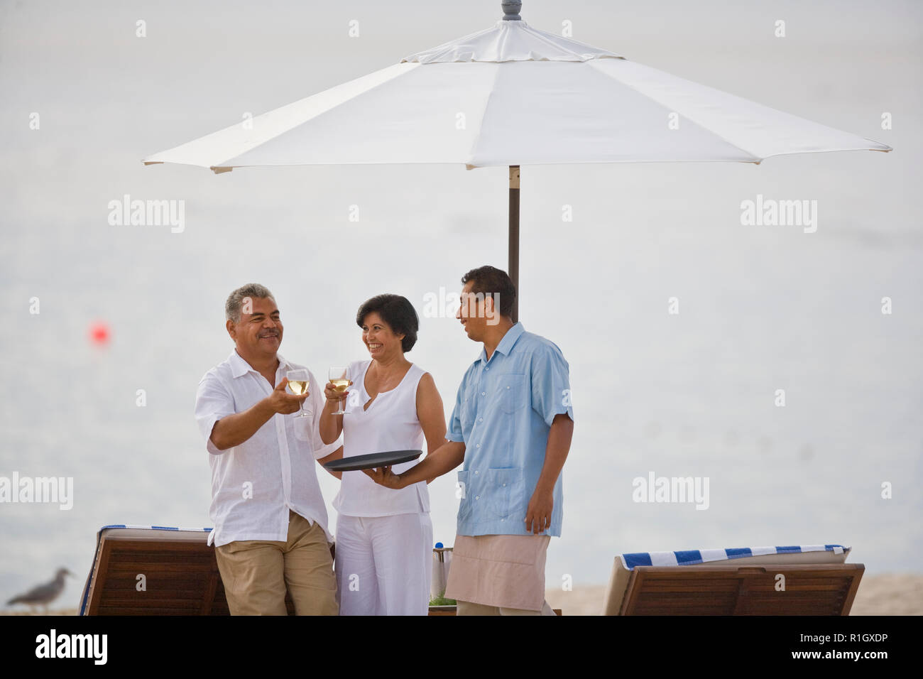 Beach Resort Kellner serviert Wein, reifes Paar Stockfoto