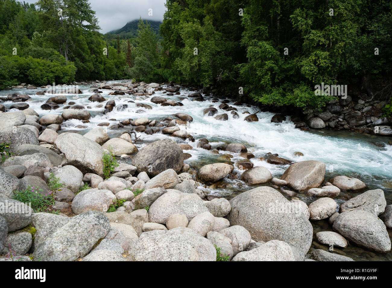 Wenig Susitna River Creek fließt durch die großen Felsen und Steine entlang des Alaska Hatcher Pass an einem bewölkten Tag Stockfoto