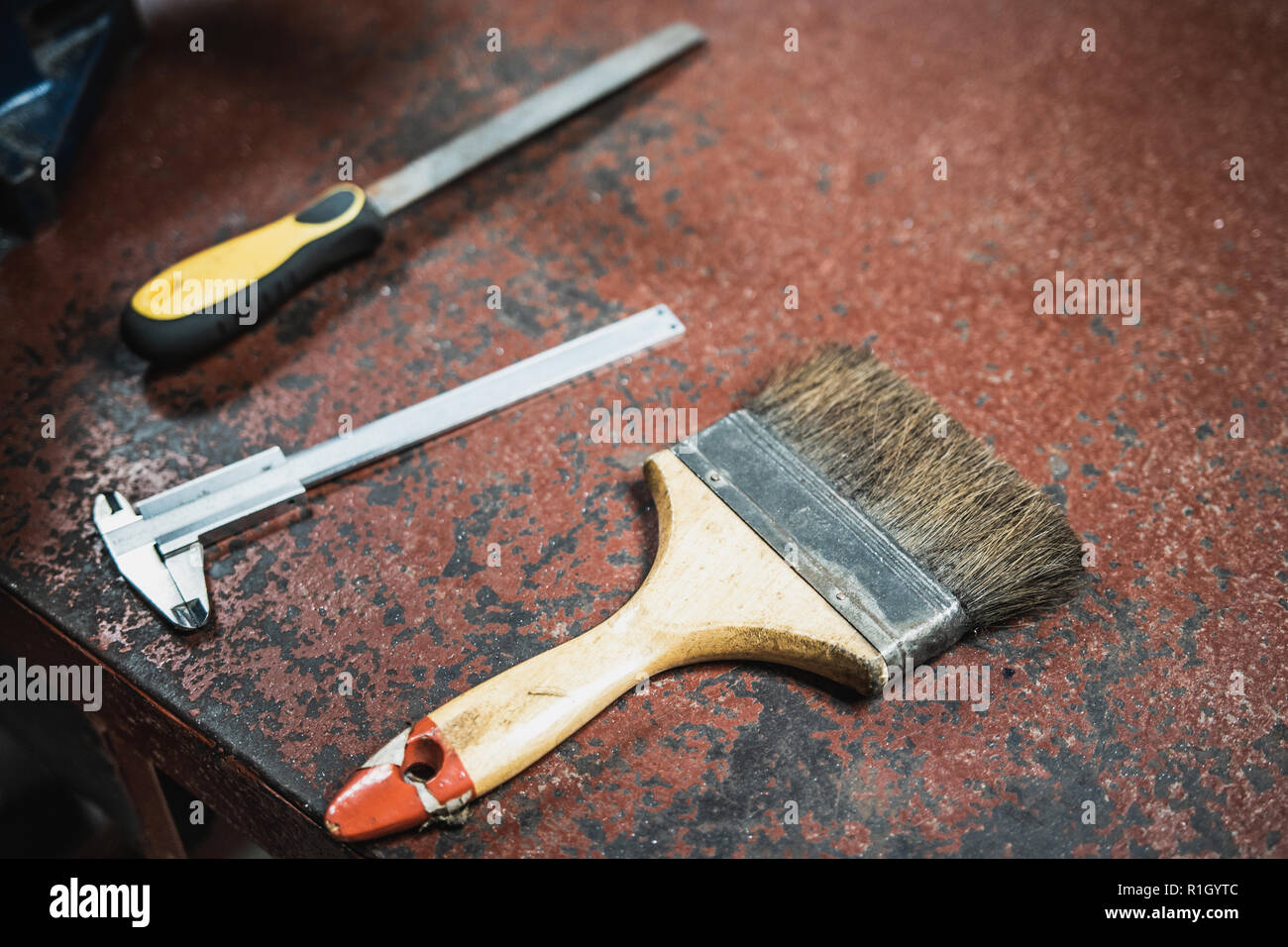 Pinsel, Messschieber, und Metall Datei auf alten metallischen workshop Bank in Rot lackiert Stockfoto