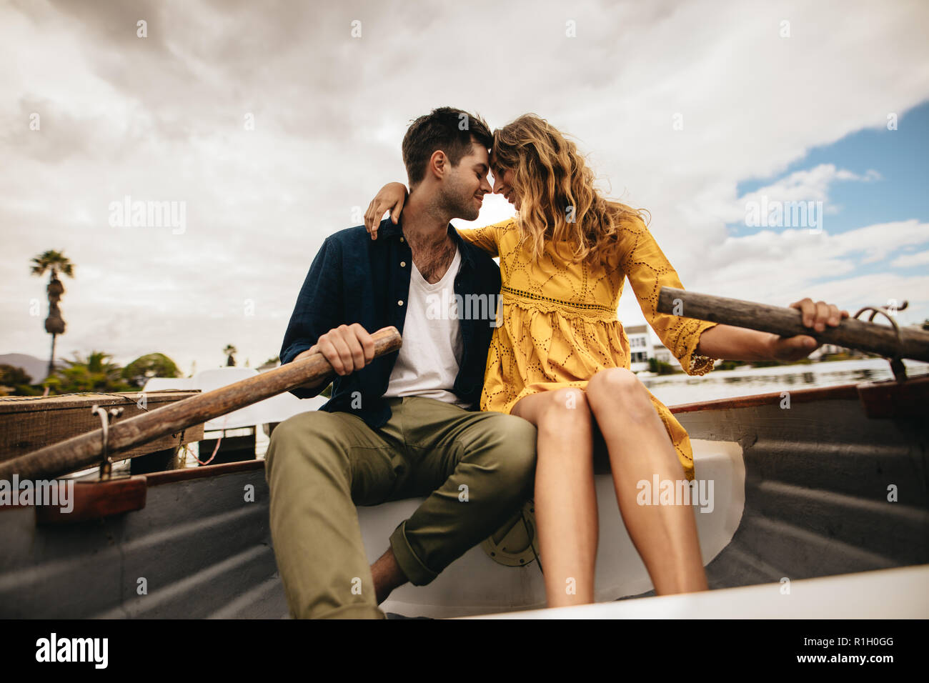 Verliebtes Paar in einem Boot sitzen entspannt miteinander halten. Junges Paar sitzen gemeinsam in einem Boot ihre Köpfe halten die Paddel berühren. Stockfoto
