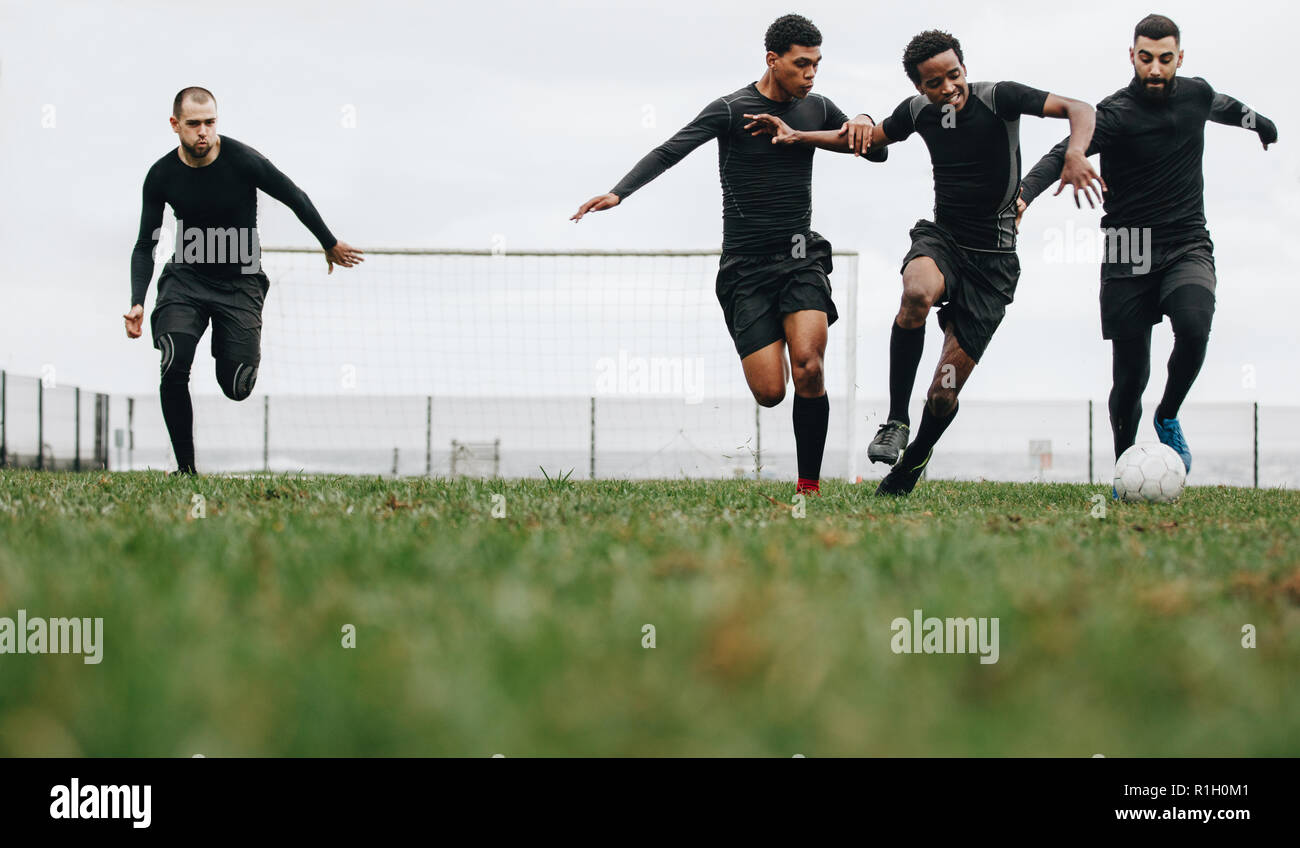 Low Angle View der Fußballer spielen auf dem Feld laufen um den Ball. Gruppe von Männern, die für den Besitz der Ball beim Fußball spielen. Stockfoto