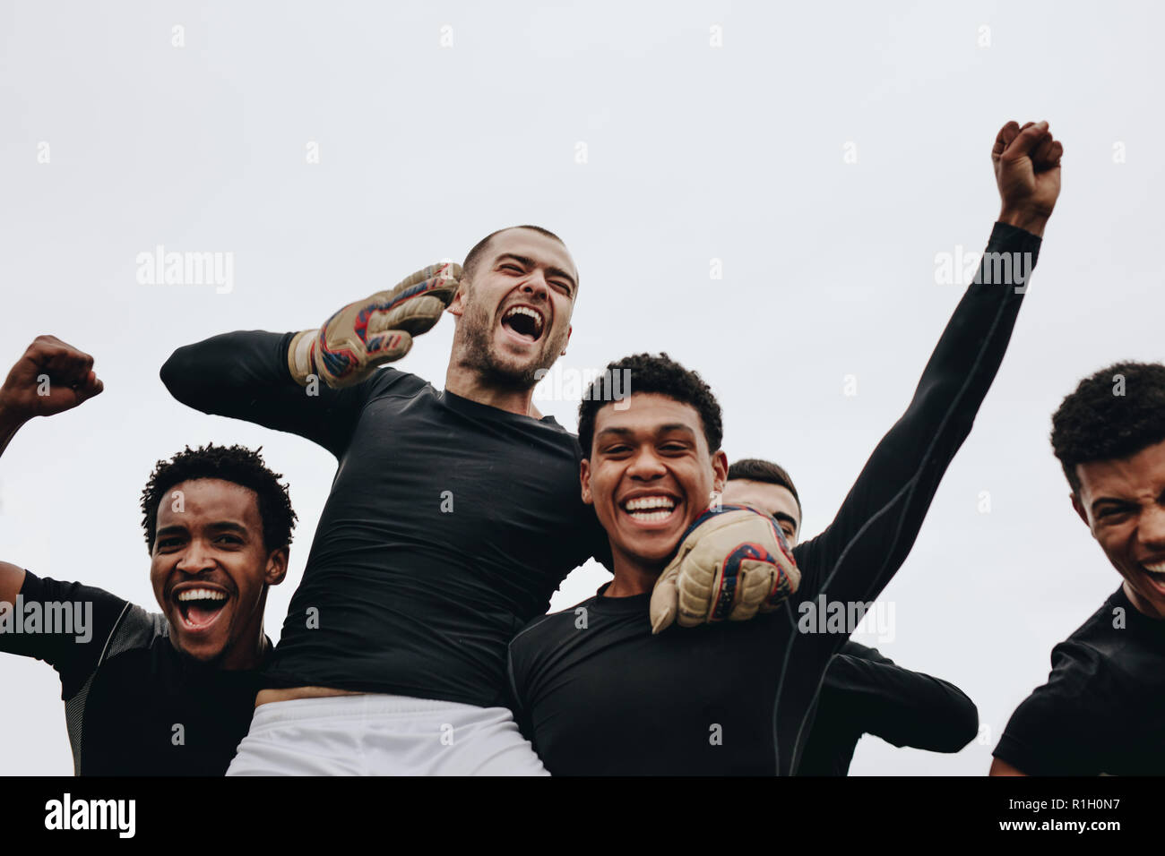 Low Angle View der Spieler ihre Mannschaftskameraden, die auf Schultern Erfolg feiern. Gruppe der gerne Fußball-Spieler feiern einen Gewinn. Stockfoto