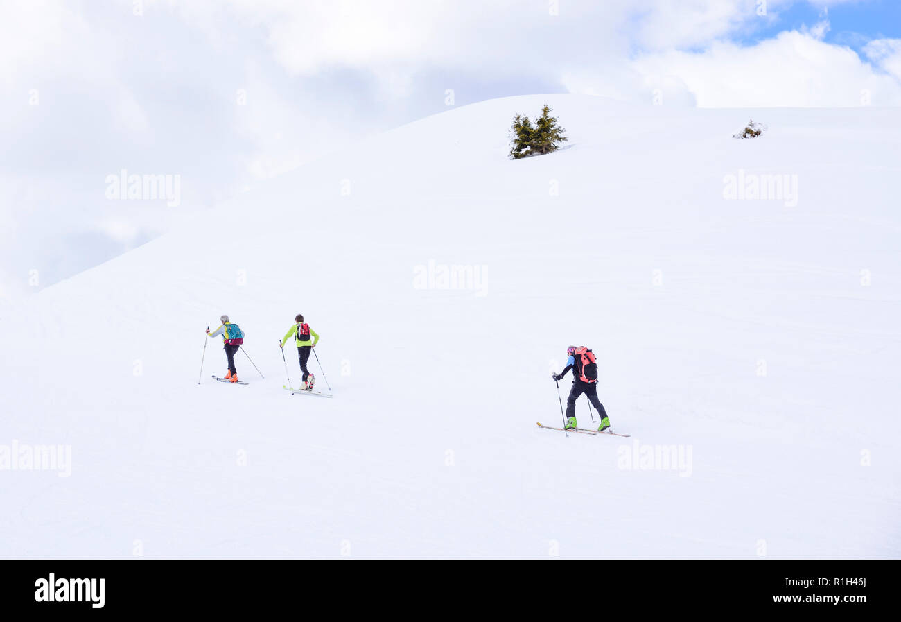 Im Schnee der Berge in den Alpen, drei Wanderer Aufstieg Richtung Gipfel Stockfoto