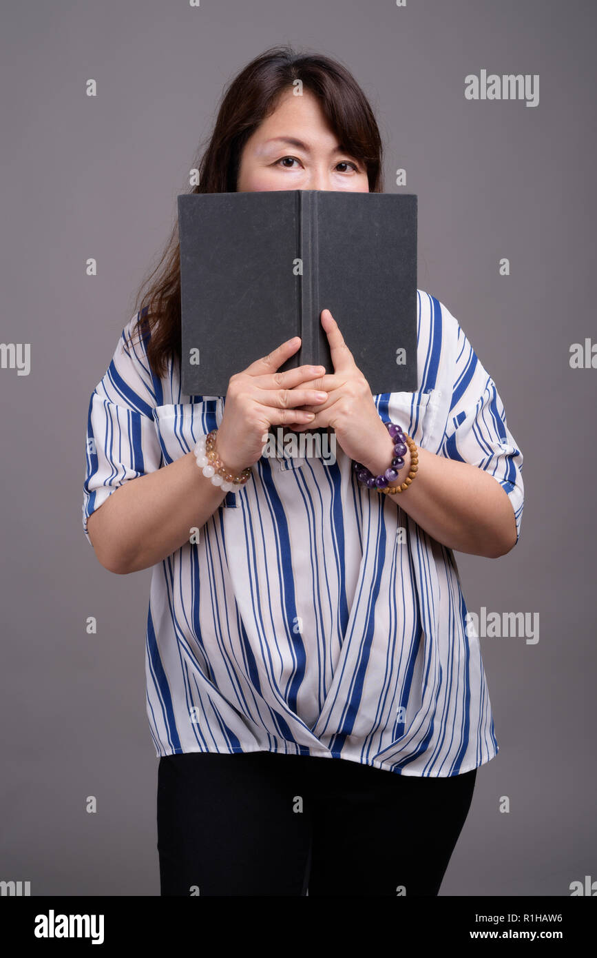 Reifen schöne asiatische Geschäftsfrau versteckt sich hinter Buch Stockfoto