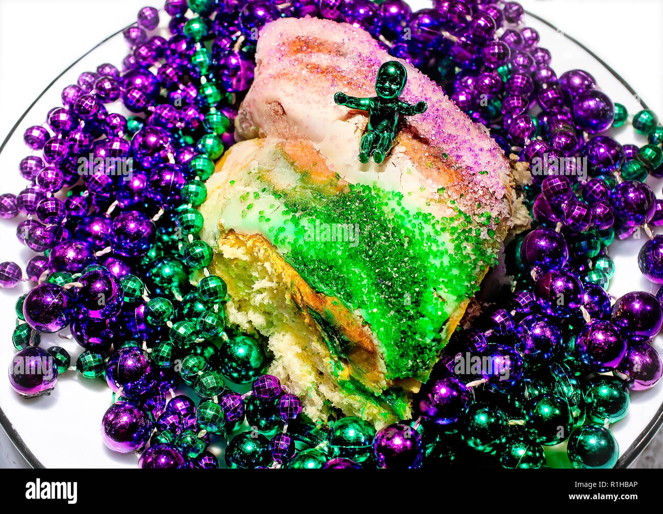 Eine Mardi Gras König Kuchen mit einem Kunststoff Baby ist dargestellt mit violetten und grünen Mardi Gras Perlen, 12. März 2014 in Mobile, Alabama. Der König Kuchen ist tr Stockfoto