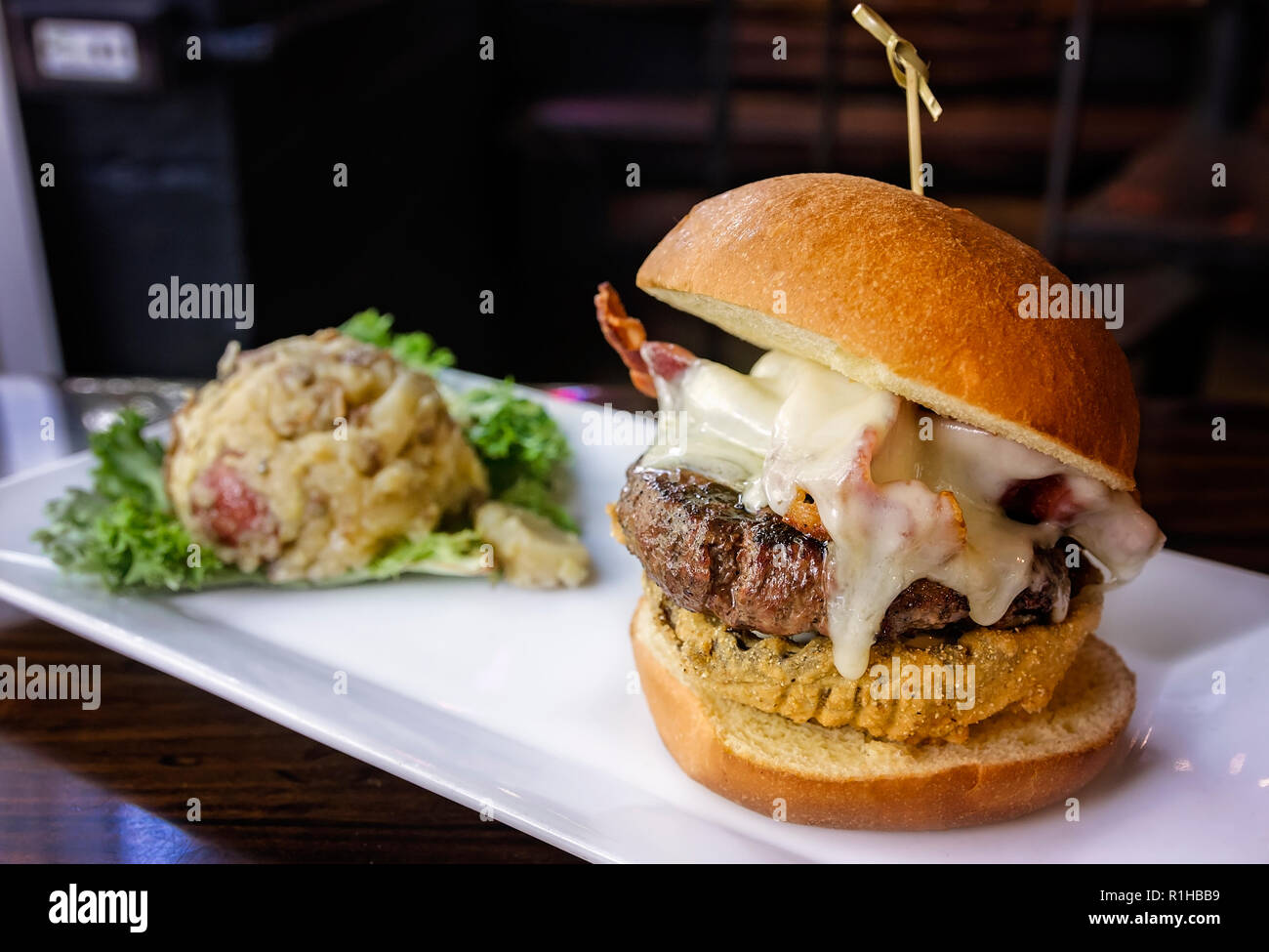 Der Saenger Gourmet Burger ist dargestellt mit deutschen Kartoffelsalat, Aug 9, 2017 at Loda Bier Garten in der Innenstadt von Mobile, Alabama. Stockfoto