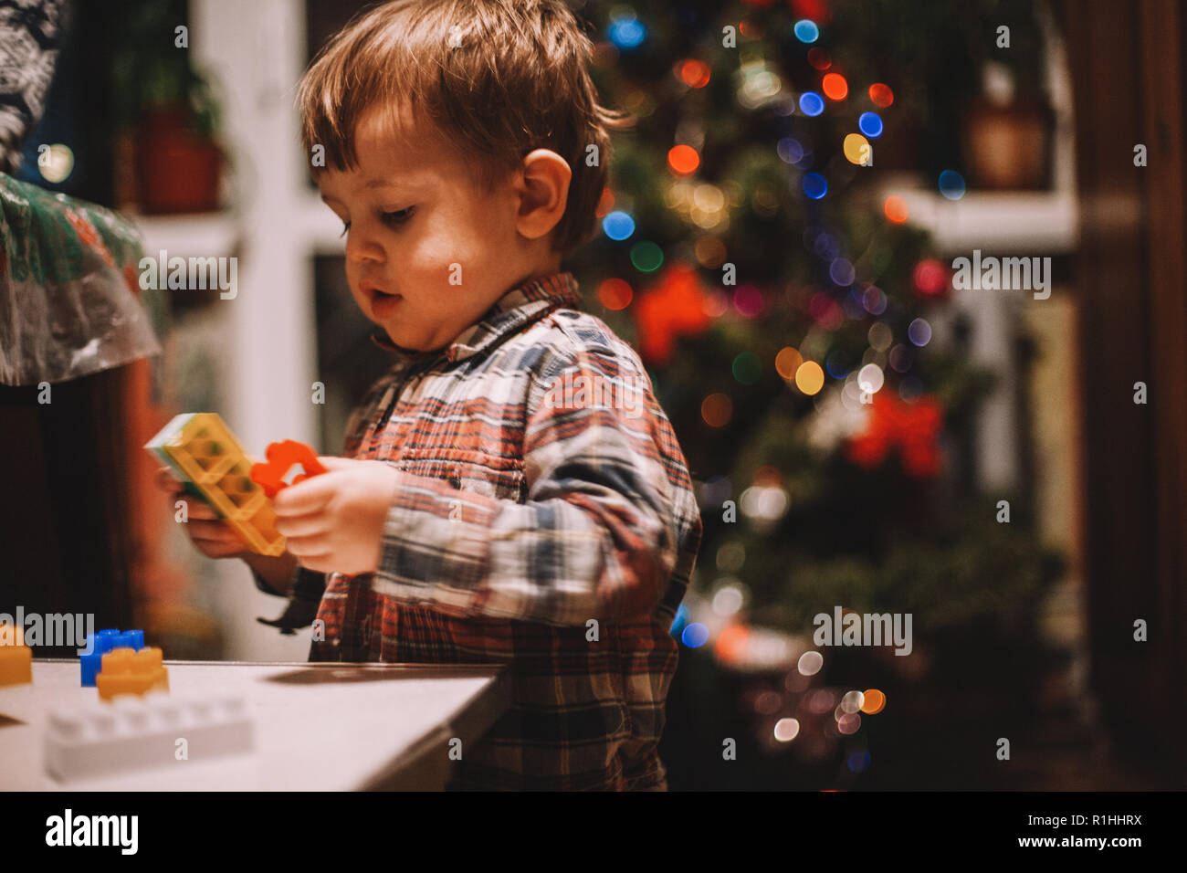 Baby Boy zu Hause spielt während der Weihnachtsfeiertage gegen Weihnachtsbaum Stockfoto