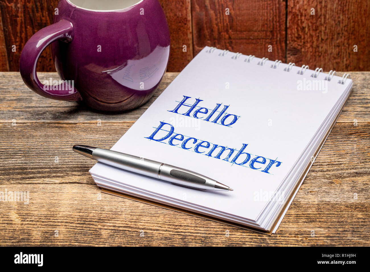 Hallo Dezember - Text in ein Skizzenbuch mit einer Tasse heißen Tee oder Kaffee og Stockfoto