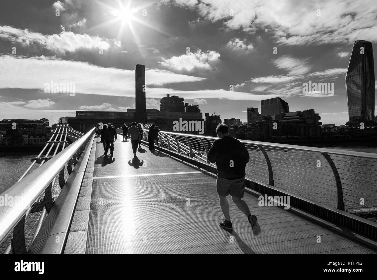 Ein Mann joggen und Menschen zu Fuß über die Millennium Bridge (wackelbrücke) London, Tate Modern Stockfoto